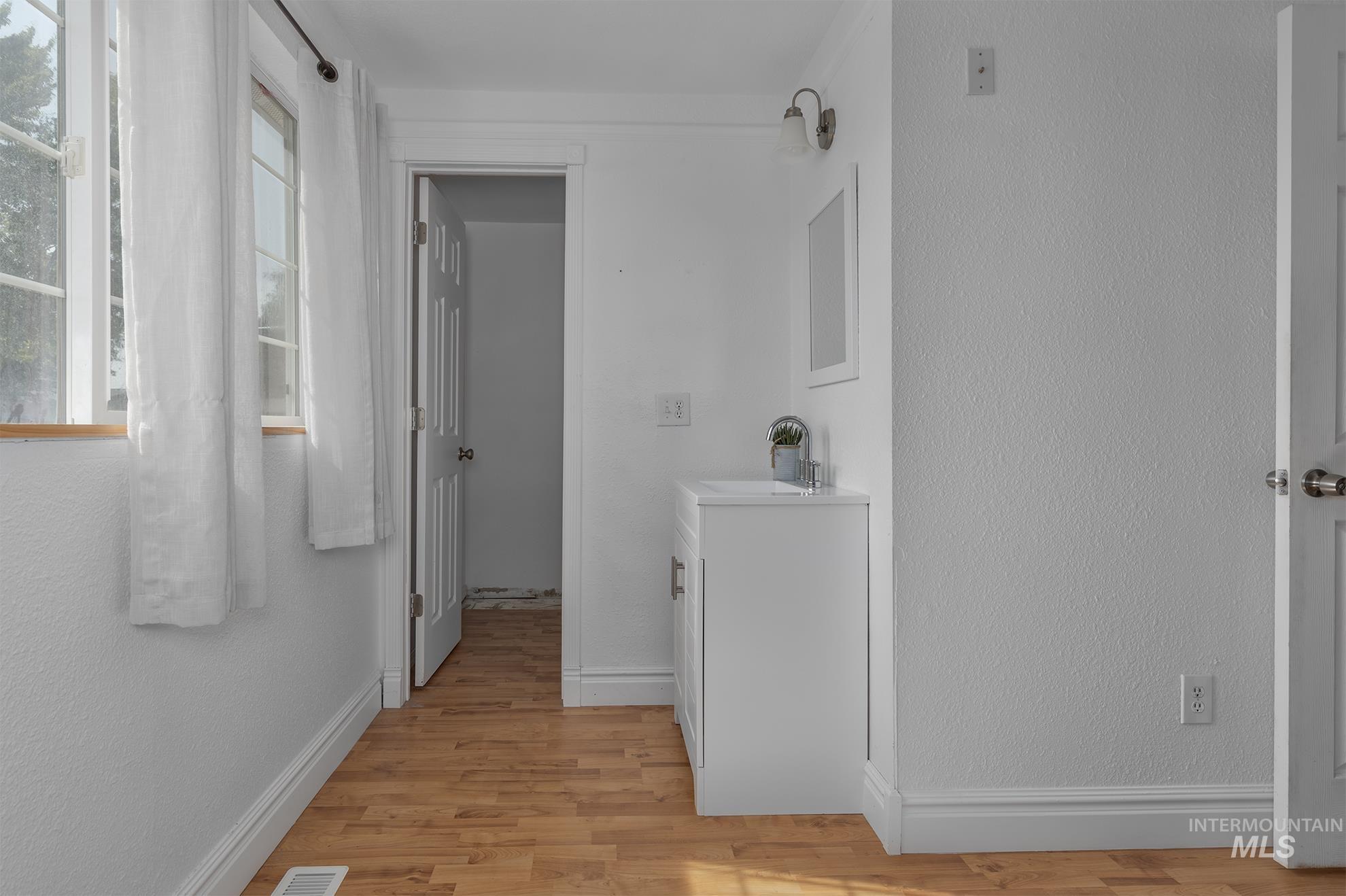 Hallway with light wood-style flooring and a textured wall