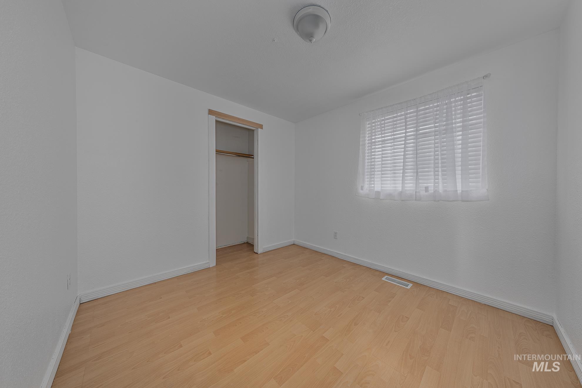 Unfurnished bedroom with light wood-type flooring and a closet