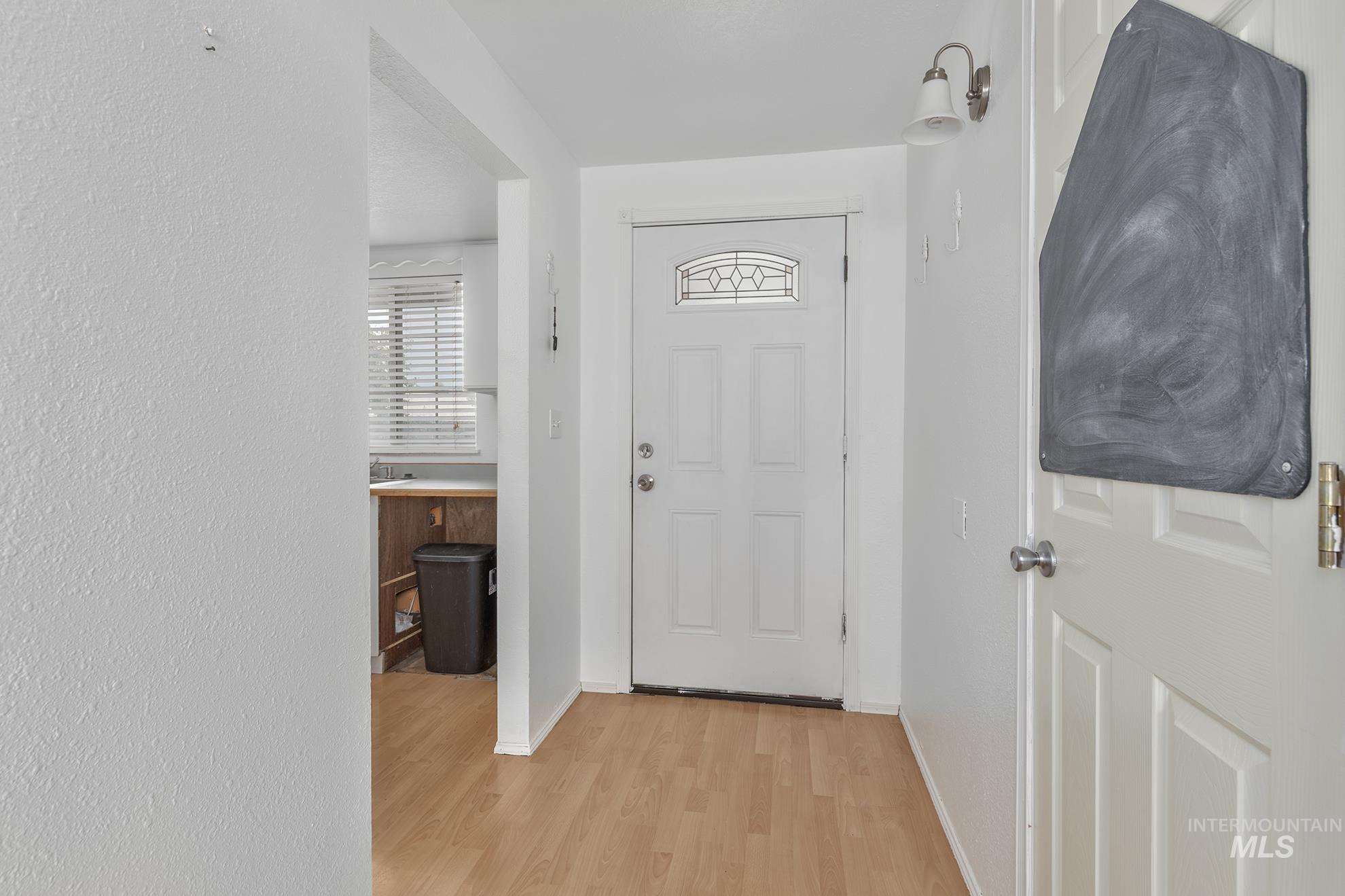Entryway with light wood-style flooring and a textured wall
