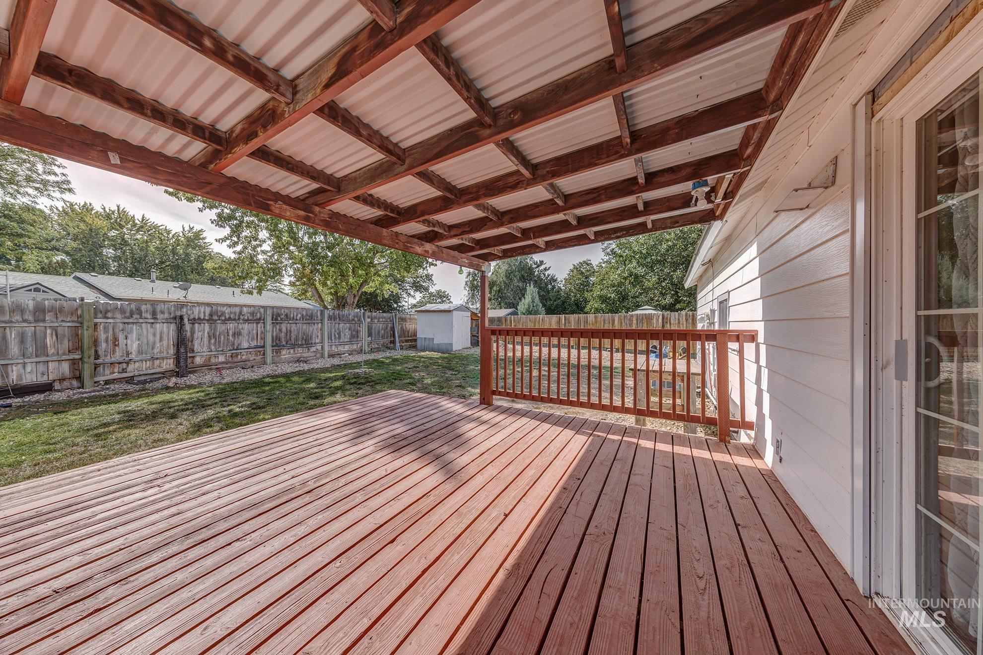 Wooden terrace with a storage unit and a fenced backyard