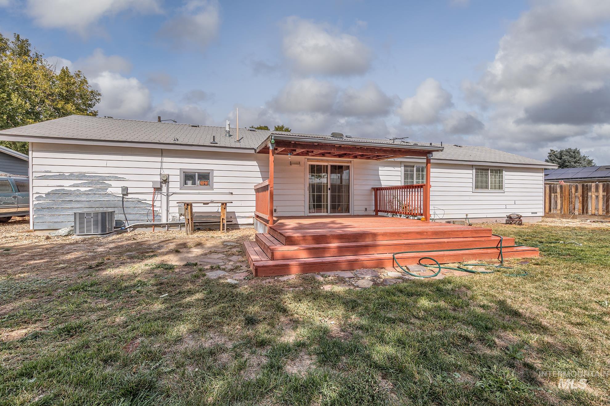 Rear view of house with a deck, a lawn, and roof with shingles
