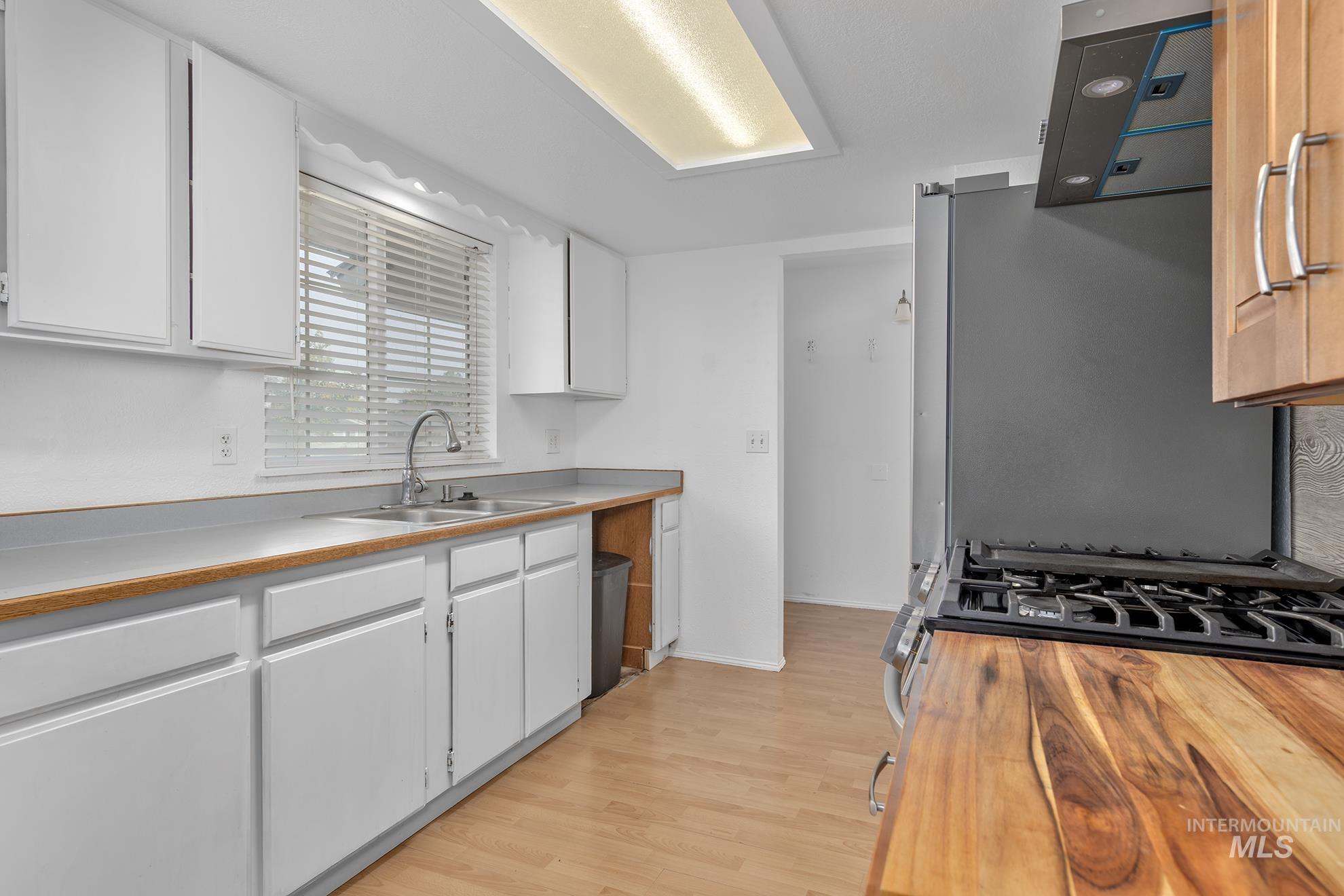 Kitchen featuring stainless steel appliances, light wood-type flooring, and white cabinets