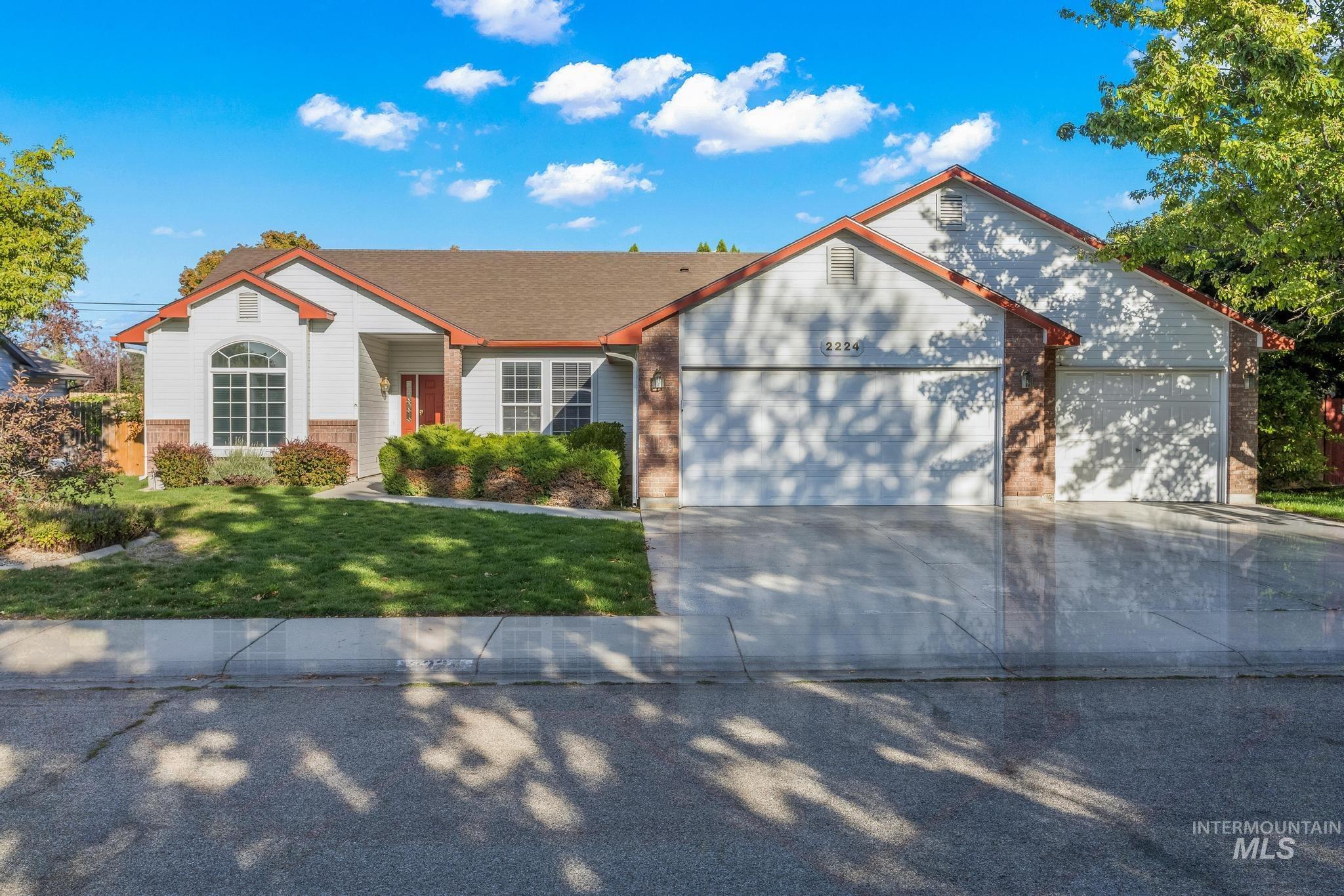 View of front of home featuring brick siding, driveway, a front lawn, and a garage