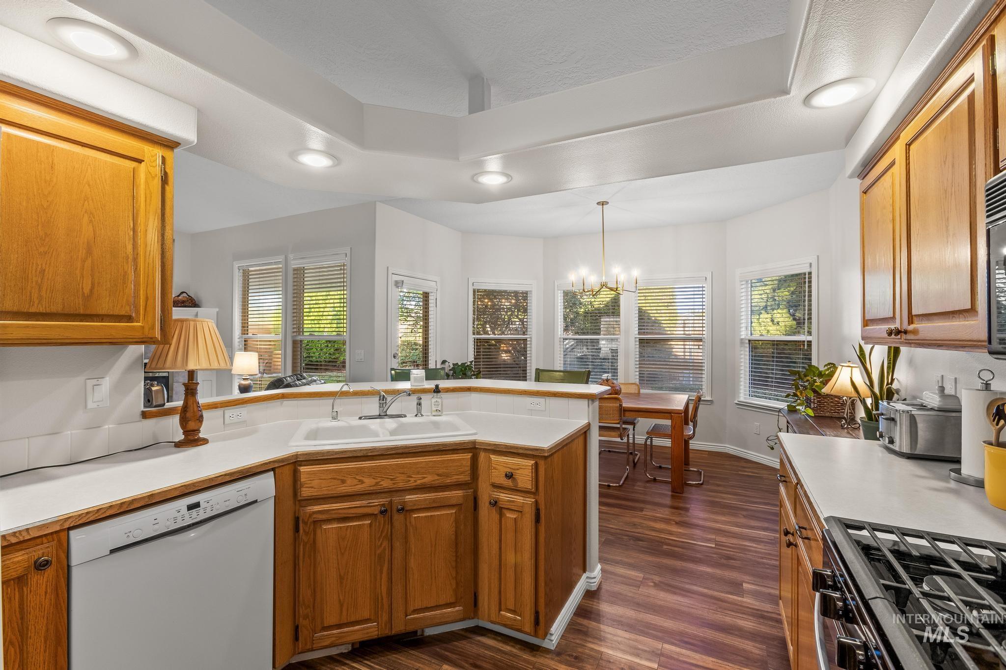 Kitchen with brown cabinets, a peninsula, dishwasher, gas range, and recessed lighting