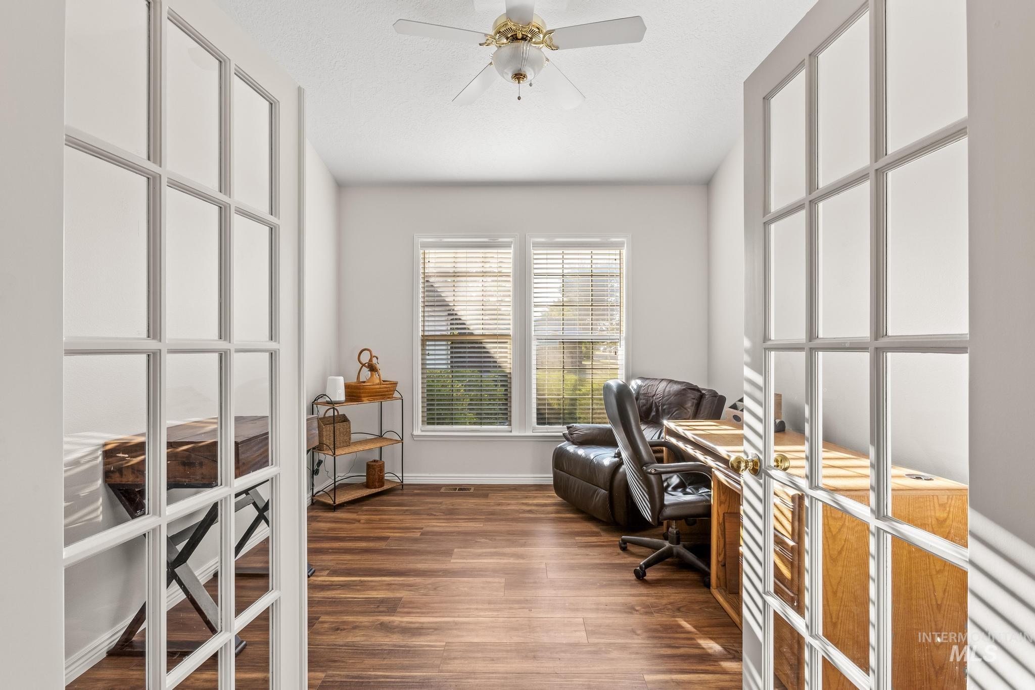 Office area with dark wood-style flooring, french doors, and a ceiling fan
