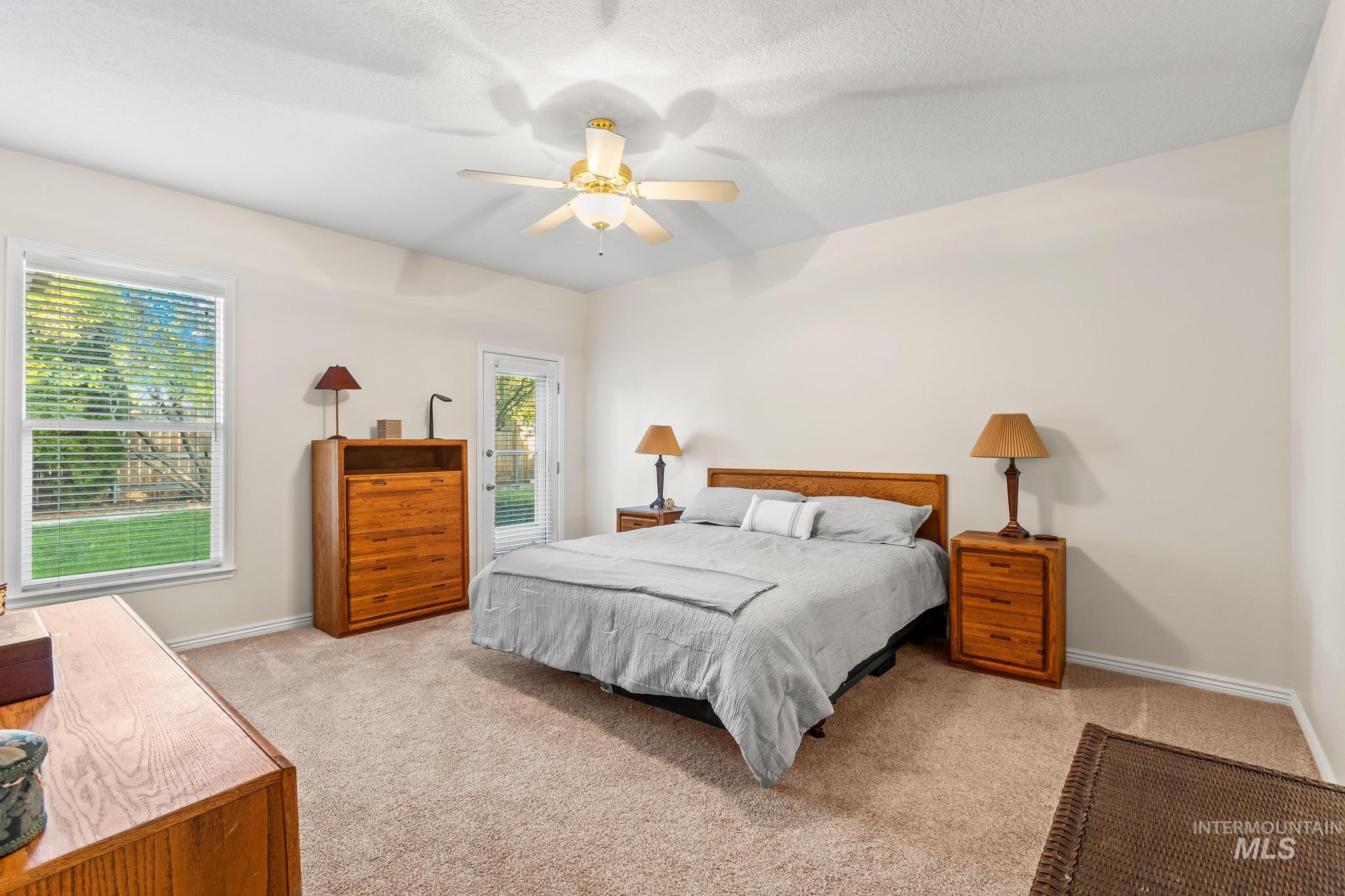 Bedroom with light colored carpet, ceiling fan, and a textured ceiling