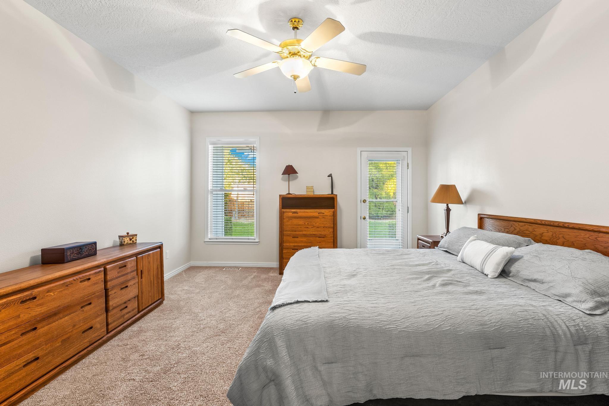 Bedroom with light carpet, a textured ceiling, access to outside, and ceiling fan