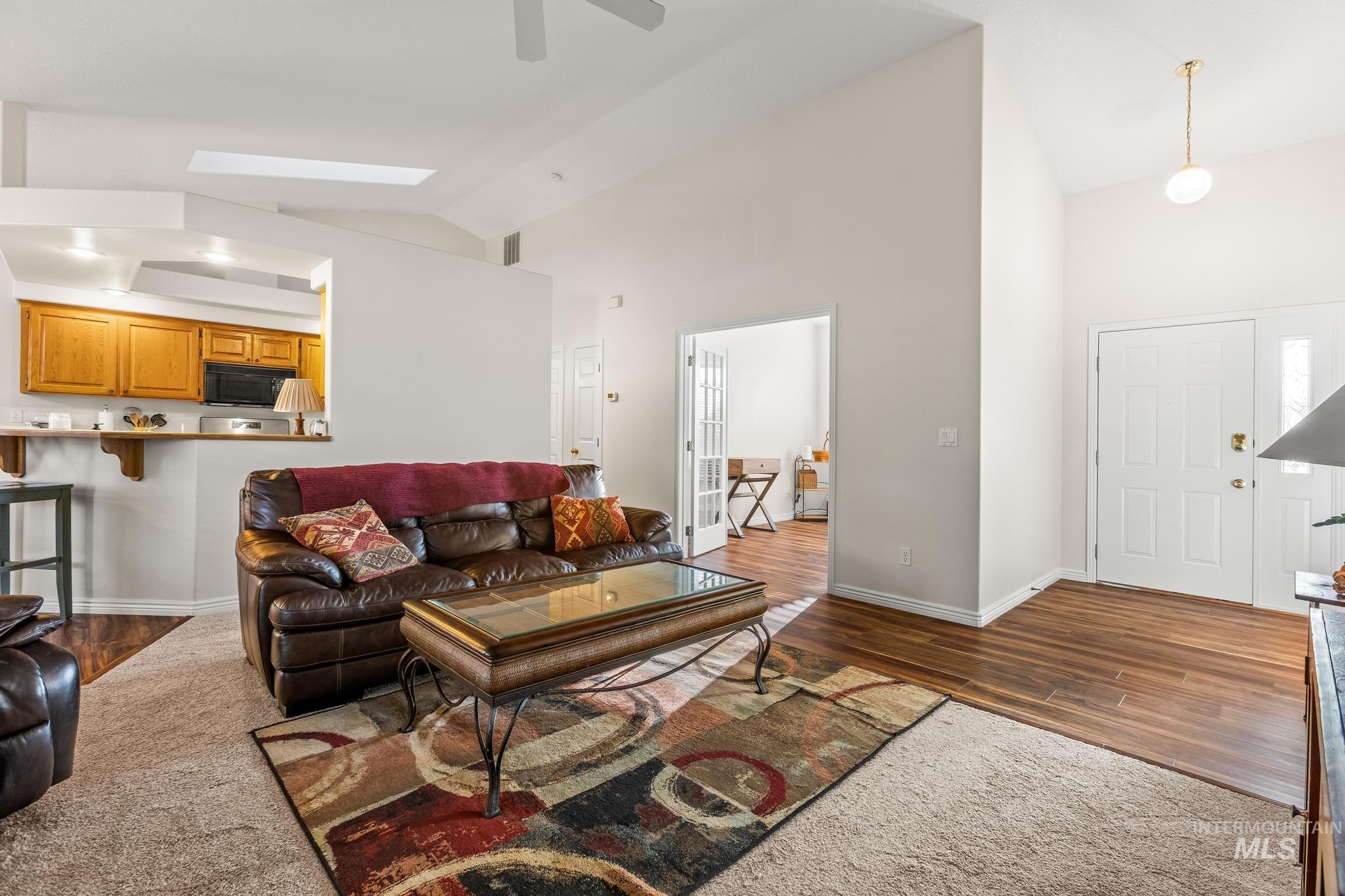 Living area with dark wood finished floors, a ceiling fan, and high vaulted ceiling