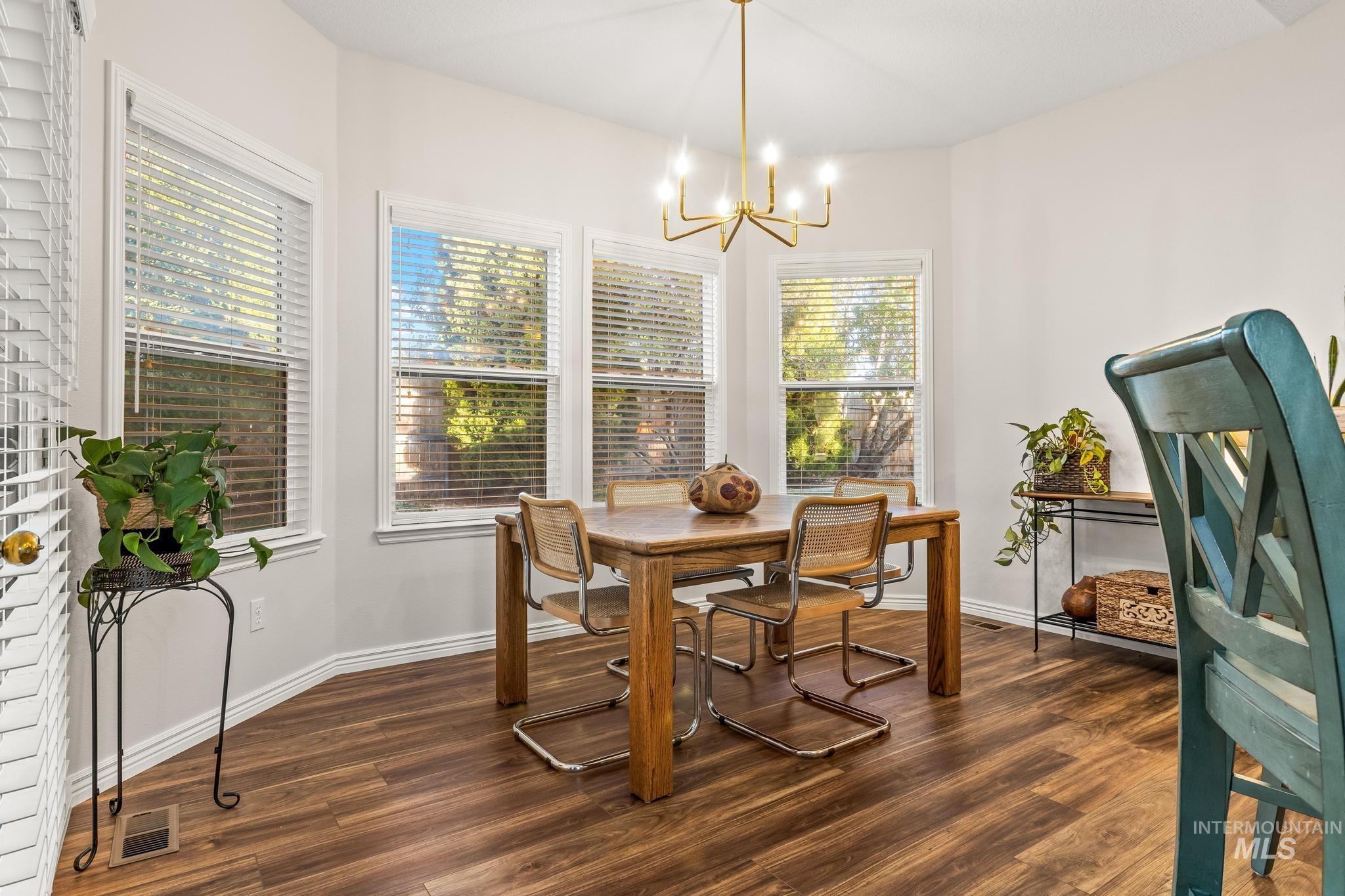 Dining room with dark wood-style floors and a chandelier