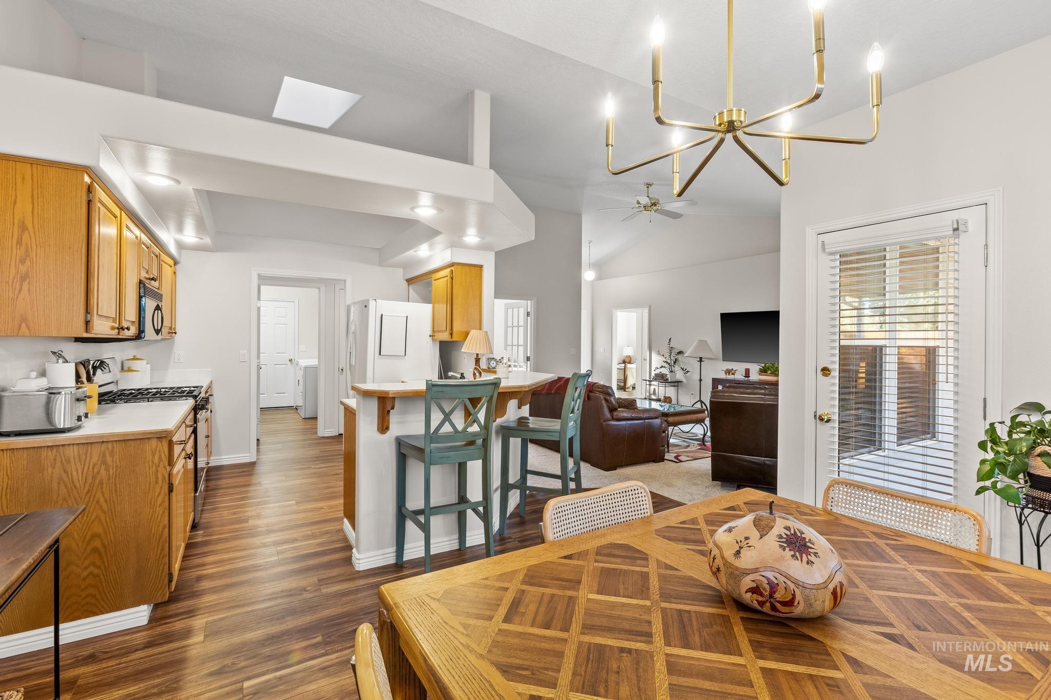 Dining room featuring dark wood finished floors, a chandelier, lofted ceiling, and ceiling fan