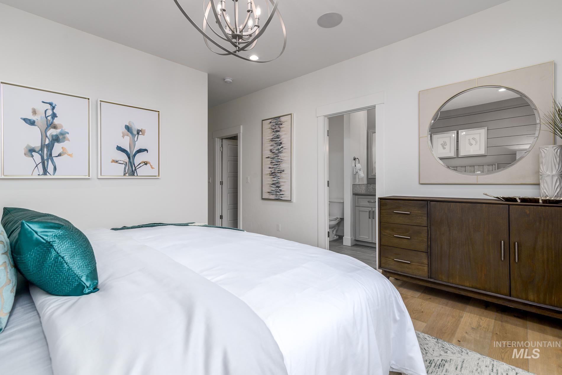Bedroom featuring light wood-style floors, a chandelier, and ensuite bathroom