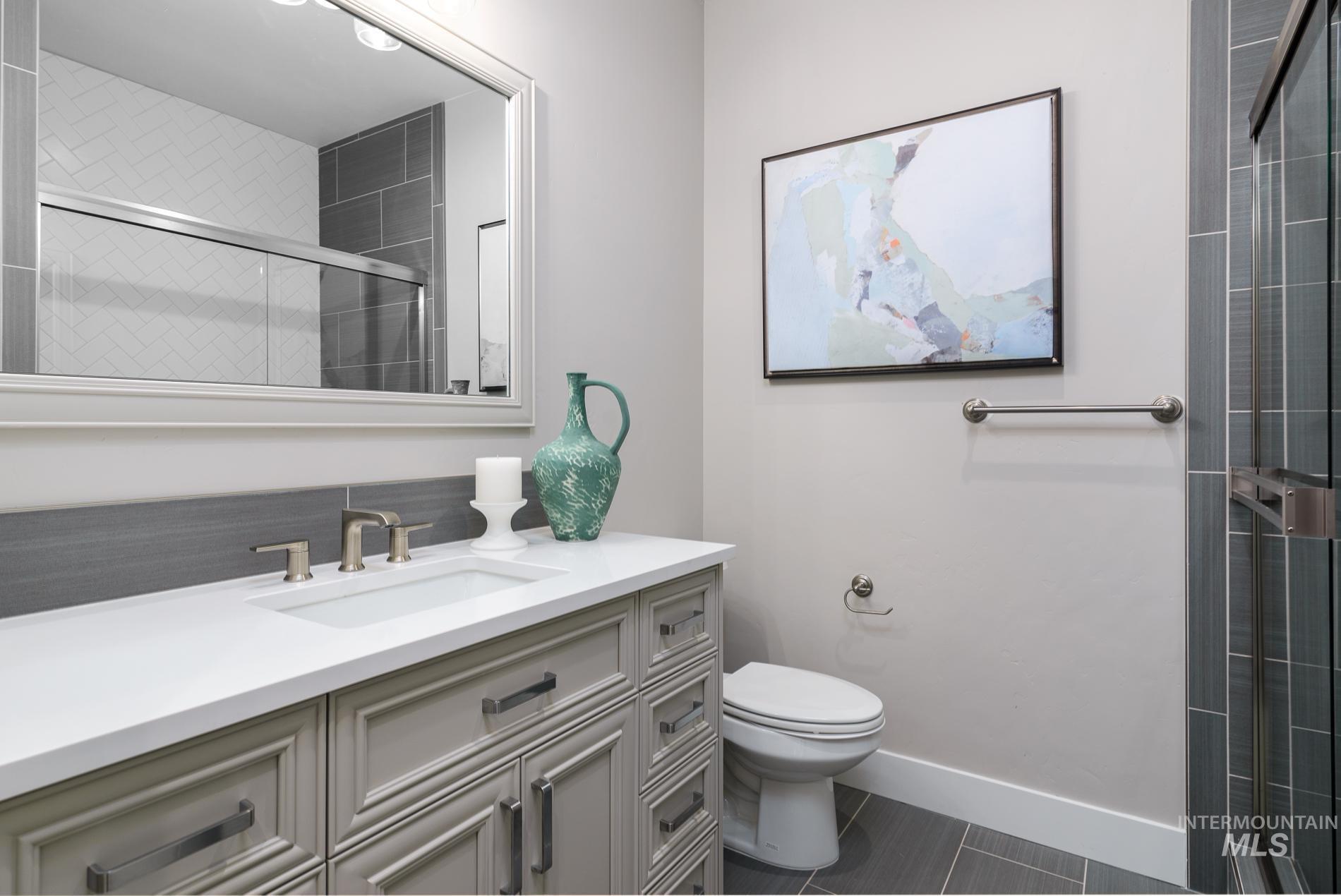 Full bath featuring vanity, a shower stall, and dark tile patterned flooring