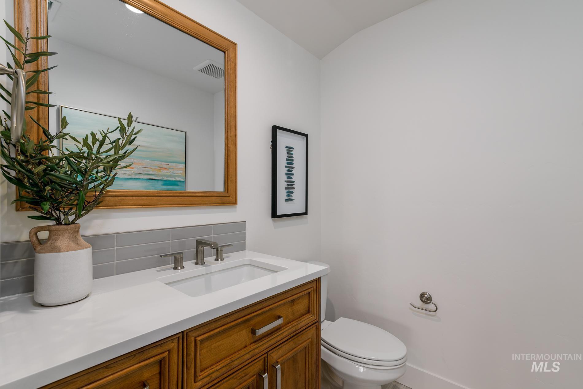 Half bath featuring vanity and backsplash