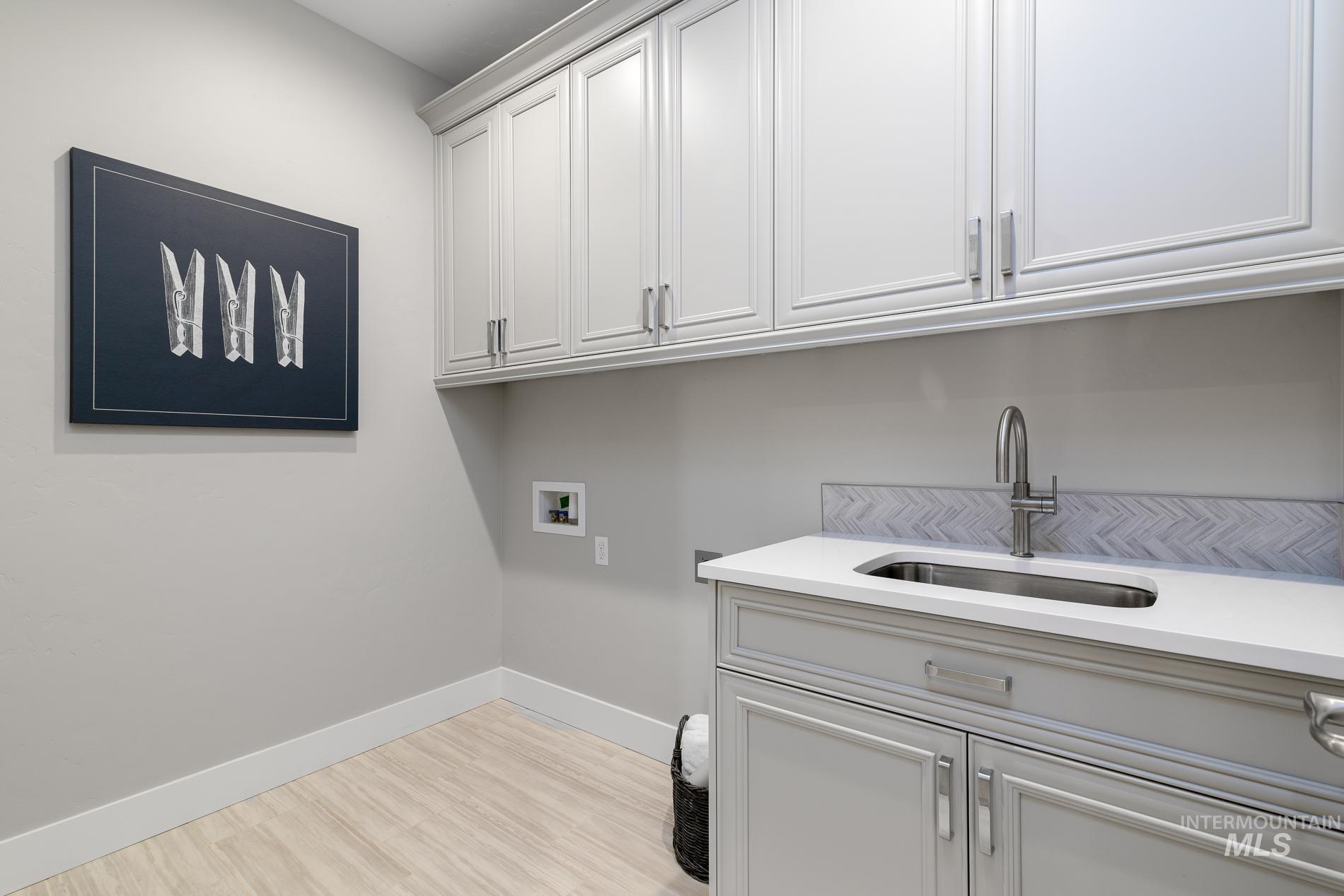 Laundry area featuring light wood finished floors, washer hookup, and cabinet space