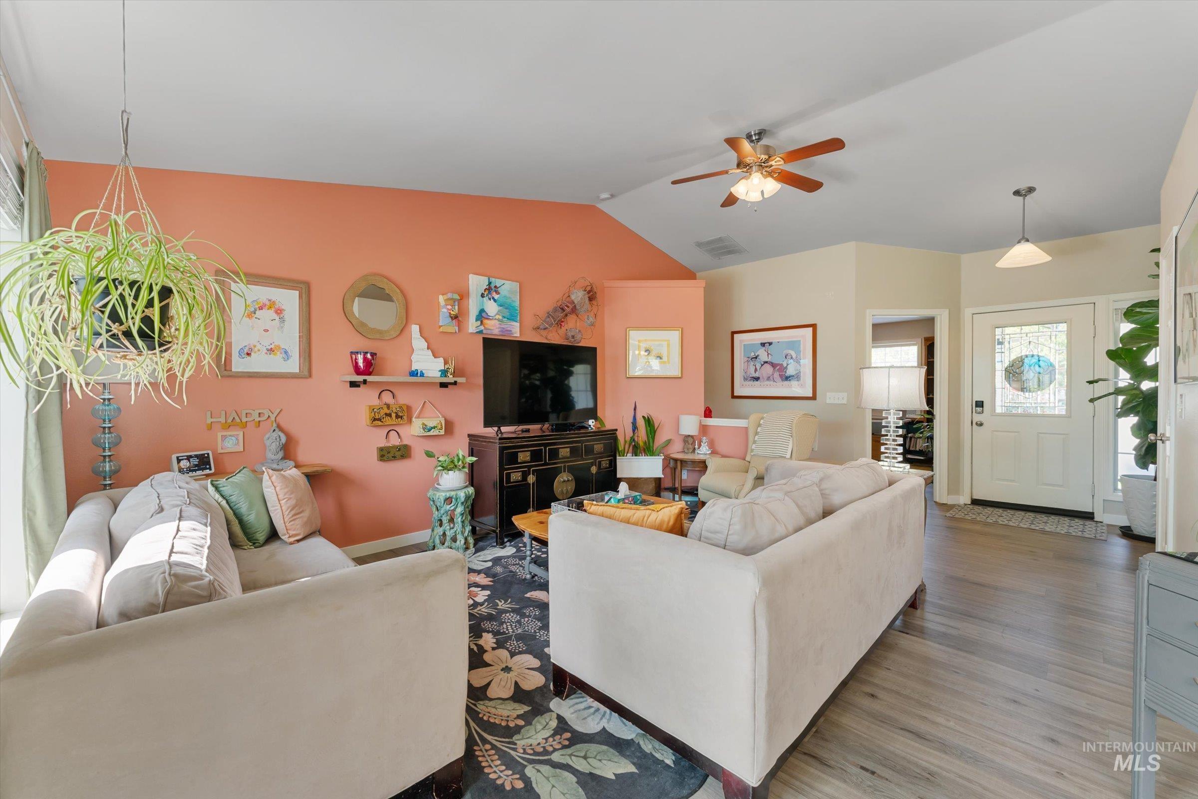 Living room featuring vaulted ceiling, wood finished floors, and ceiling fan