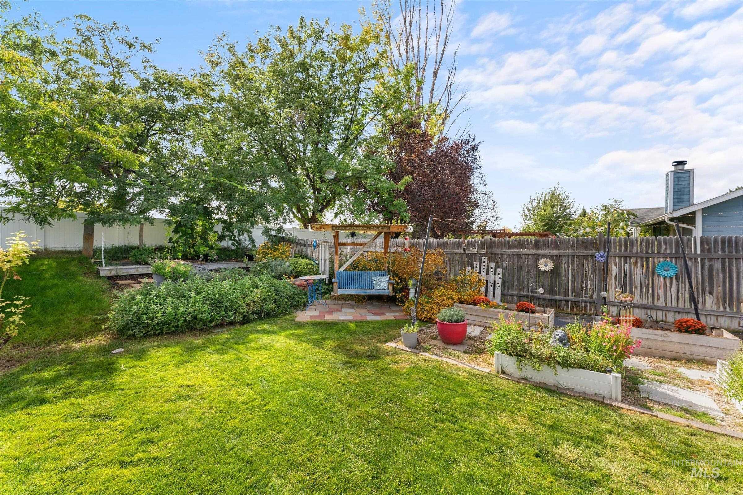 Fenced backyard featuring a vegetable garden and a patio area