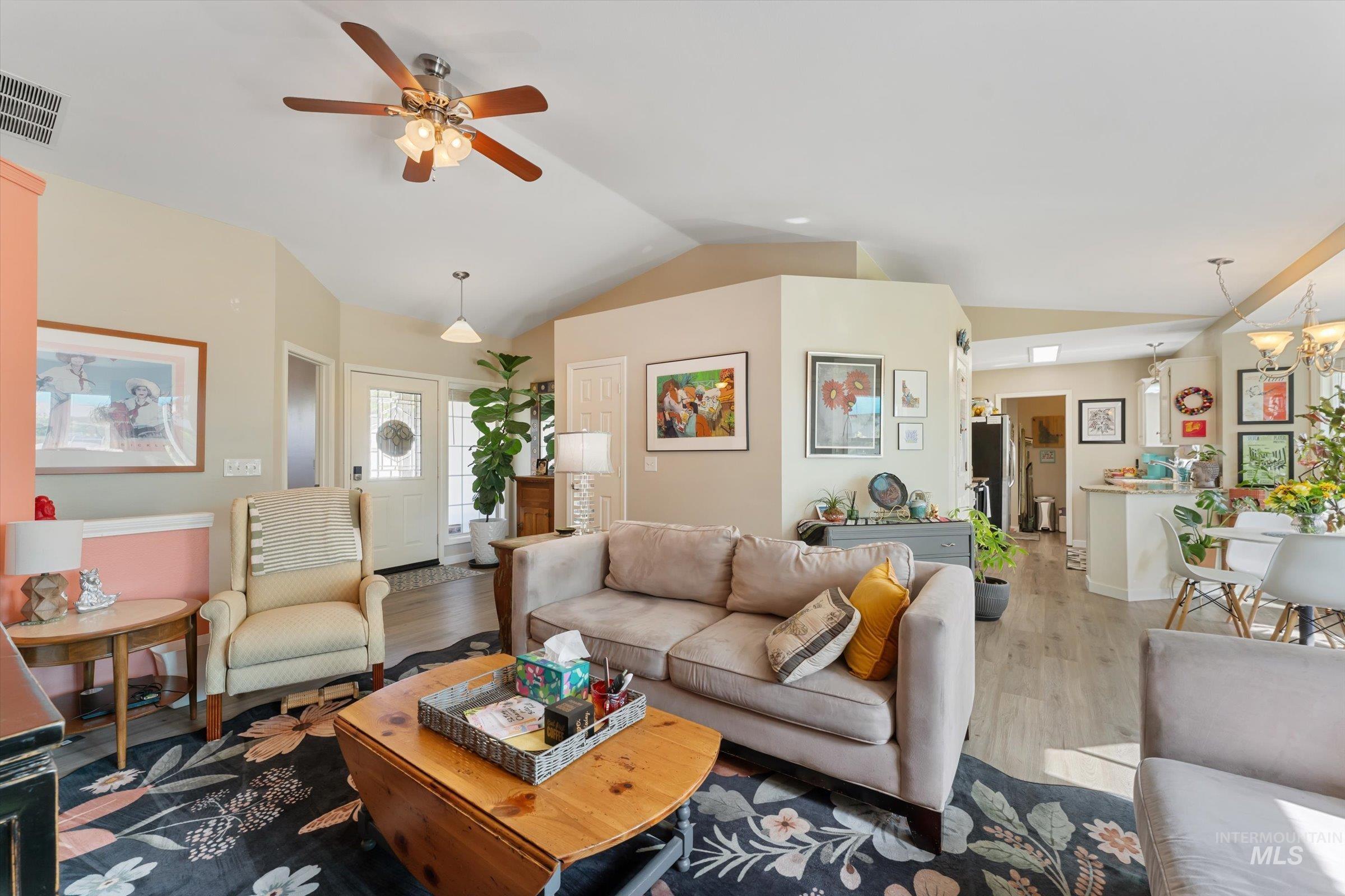 Living area with vaulted ceiling, wood finished floors, and a ceiling fan