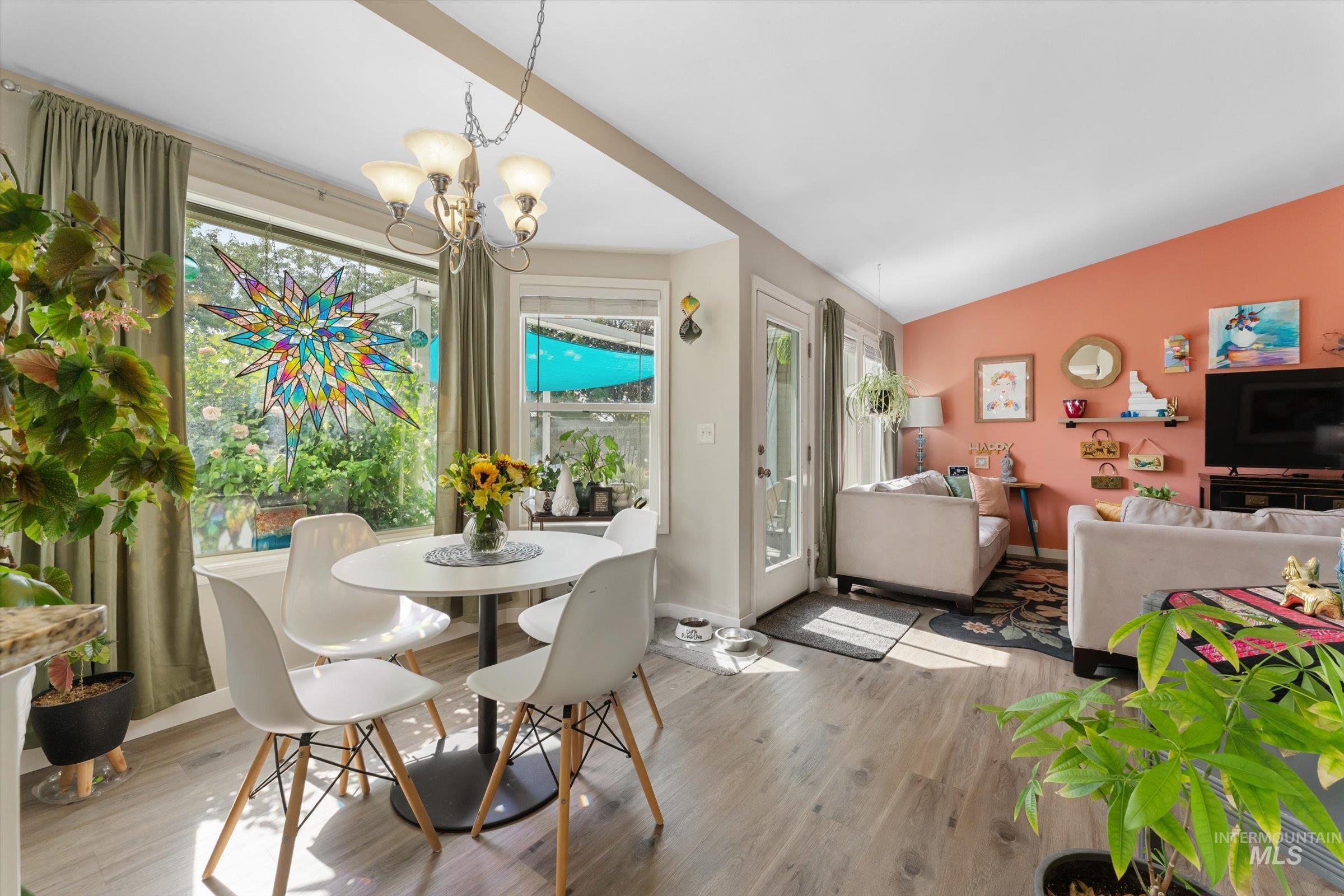 Dining space featuring wood finished floors, vaulted ceiling, and a chandelier