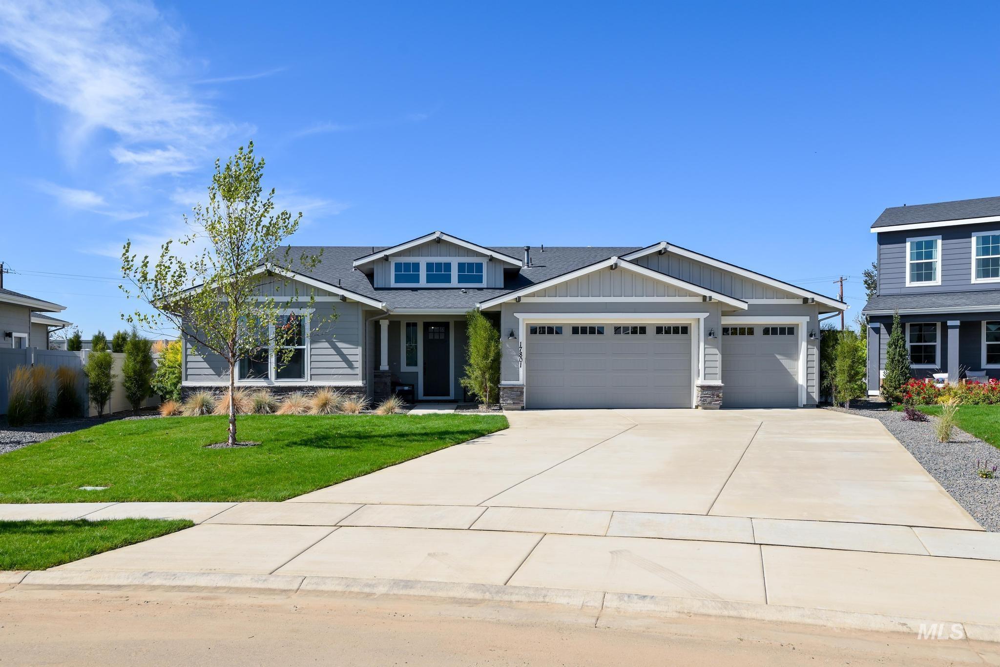 Craftsman house featuring stone siding, a front lawn, a garage, board and batten siding, and driveway