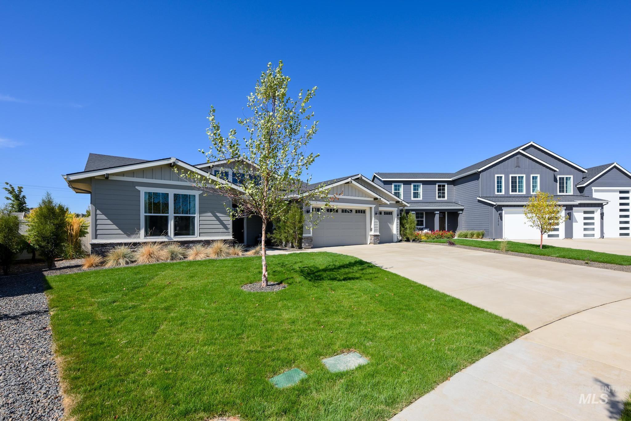 View of front facade with board and batten siding, concrete driveway, a front lawn, and an attached garage