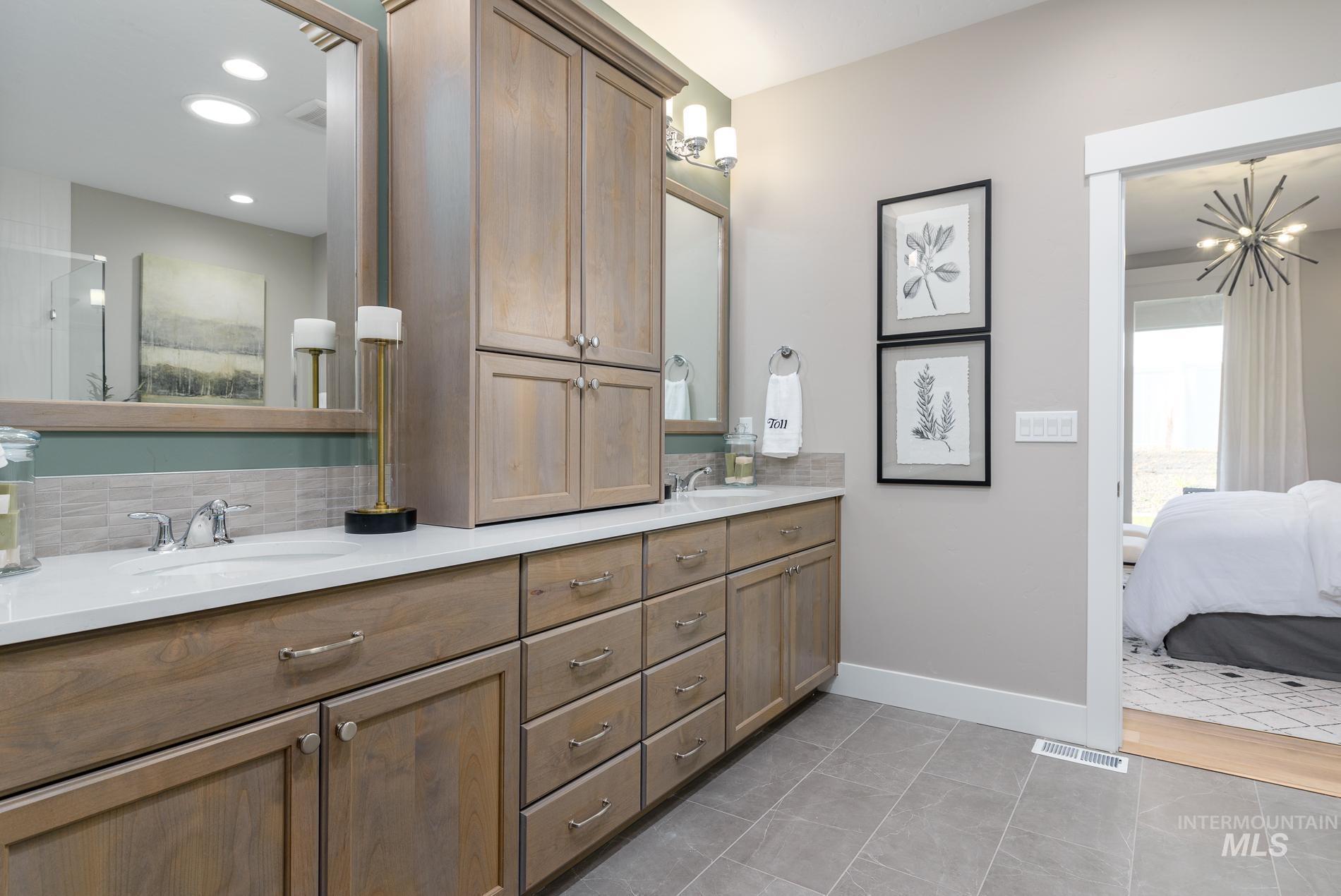Ensuite bathroom featuring double vanity, light tile patterned flooring, a chandelier, recessed lighting, and decorative backsplash