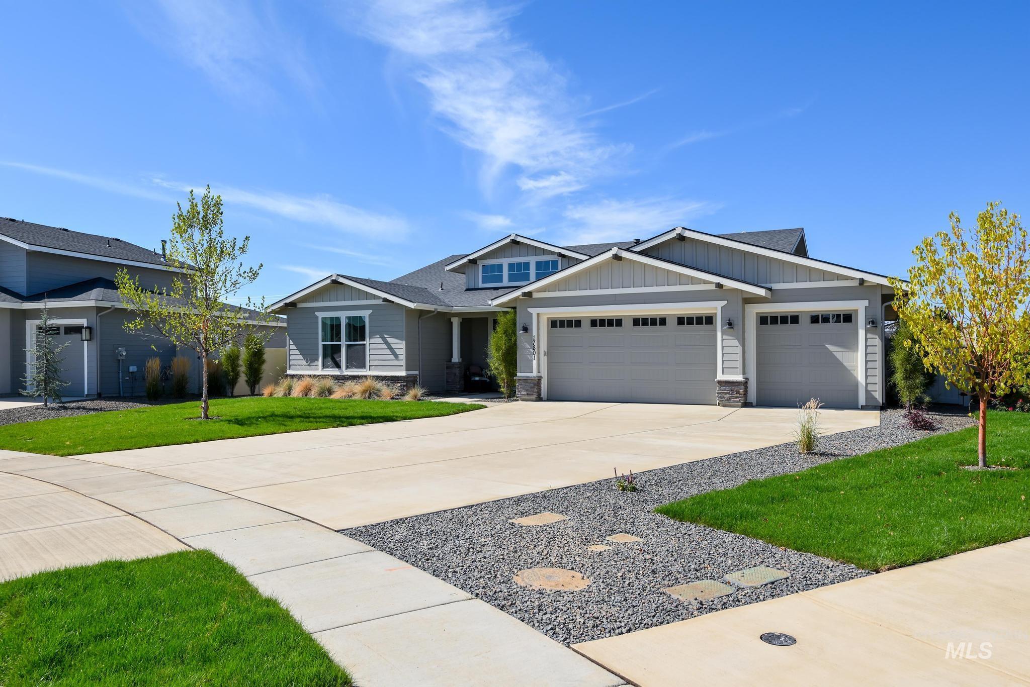 Craftsman-style home featuring stone siding, driveway, an attached garage, a front lawn, and board and batten siding