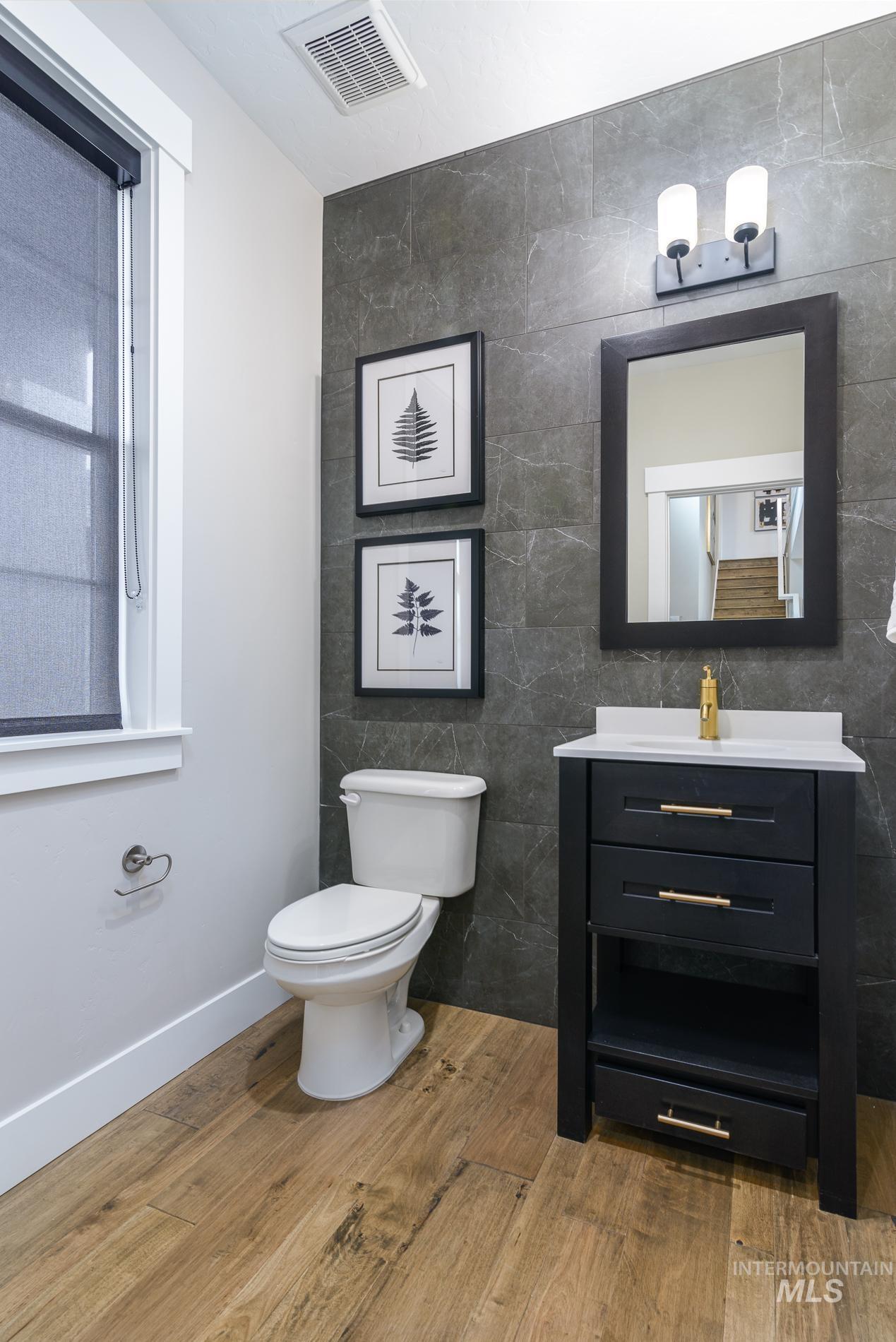 Bathroom featuring tile walls, light wood-style floors, and vanity