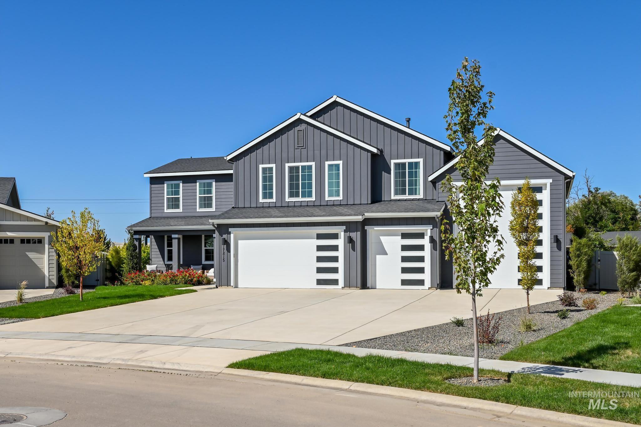 View of front facade featuring concrete driveway, an attached garage, board and batten siding, and a front lawn