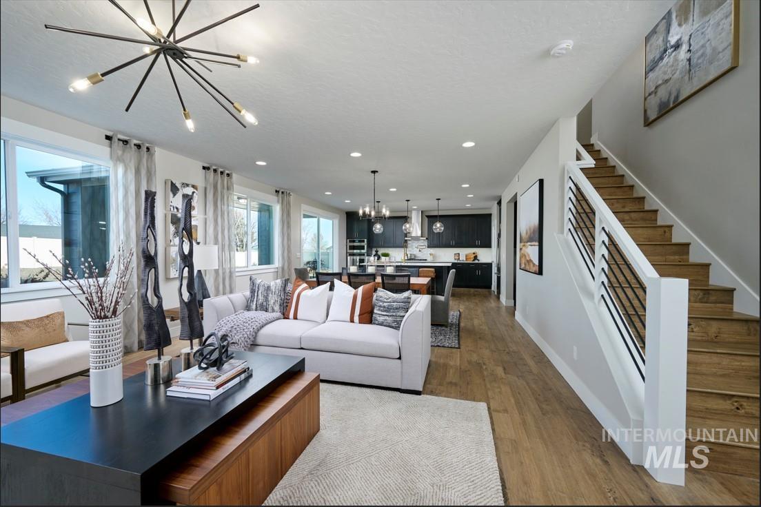 Living area with a chandelier, dark wood-style flooring, recessed lighting, and stairway