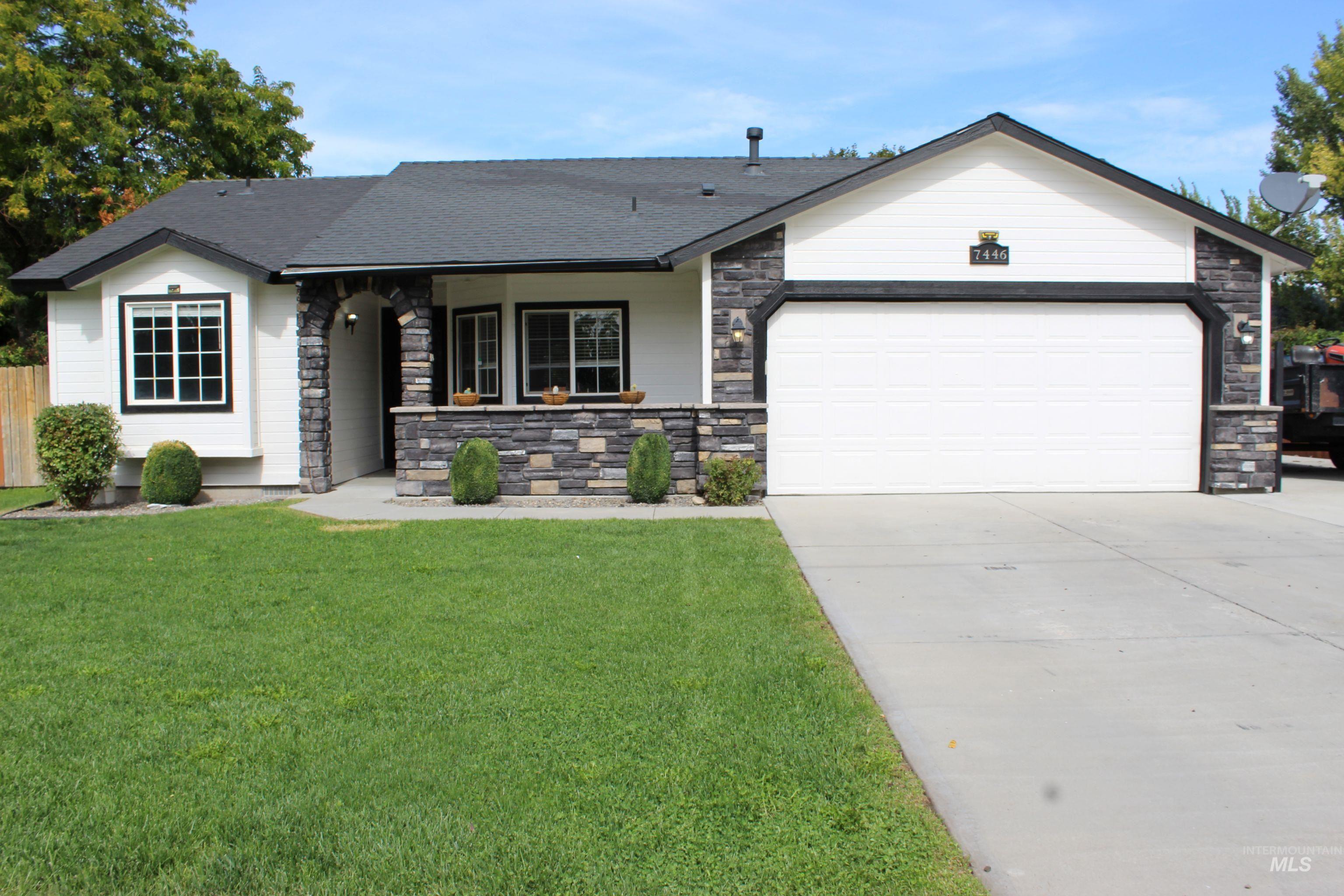 View of front facade with stone siding, concrete driveway, a front yard, and an attached garage