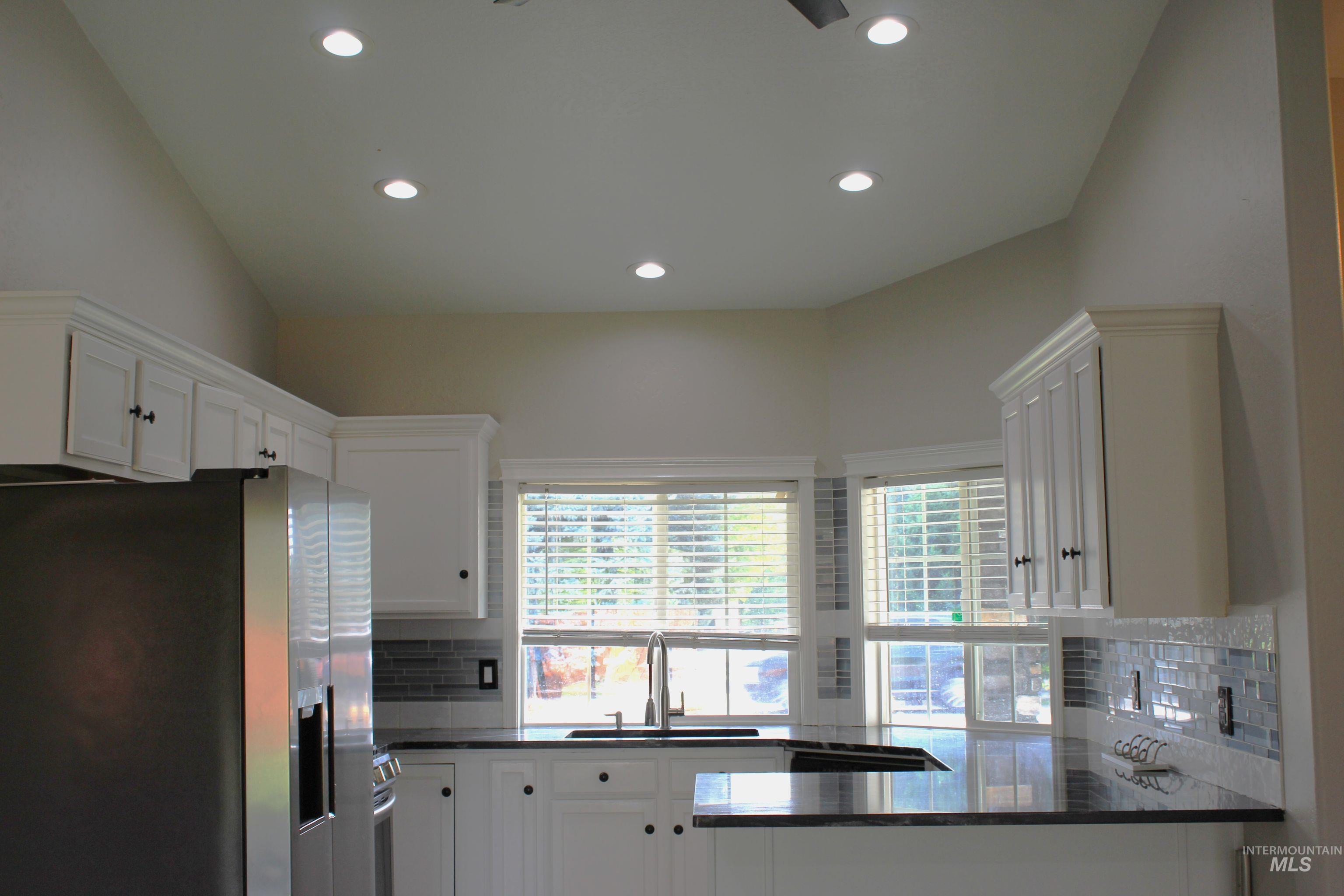 Kitchen with stainless steel fridge with ice dispenser, tasteful backsplash, white cabinets, and recessed lighting