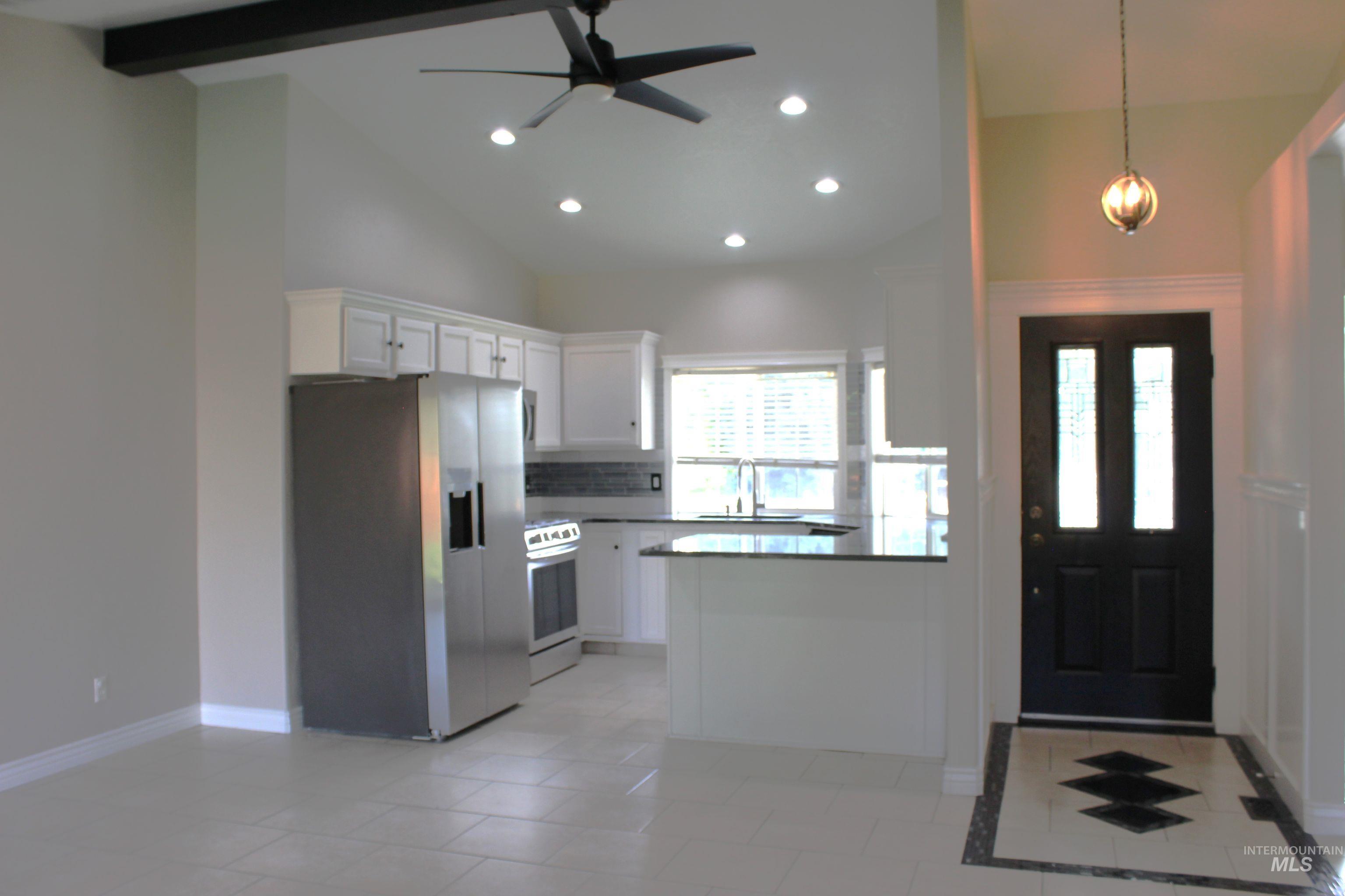 Kitchen with stainless steel fridge with ice dispenser, white cabinetry, vaulted ceiling, recessed lighting, and electric range