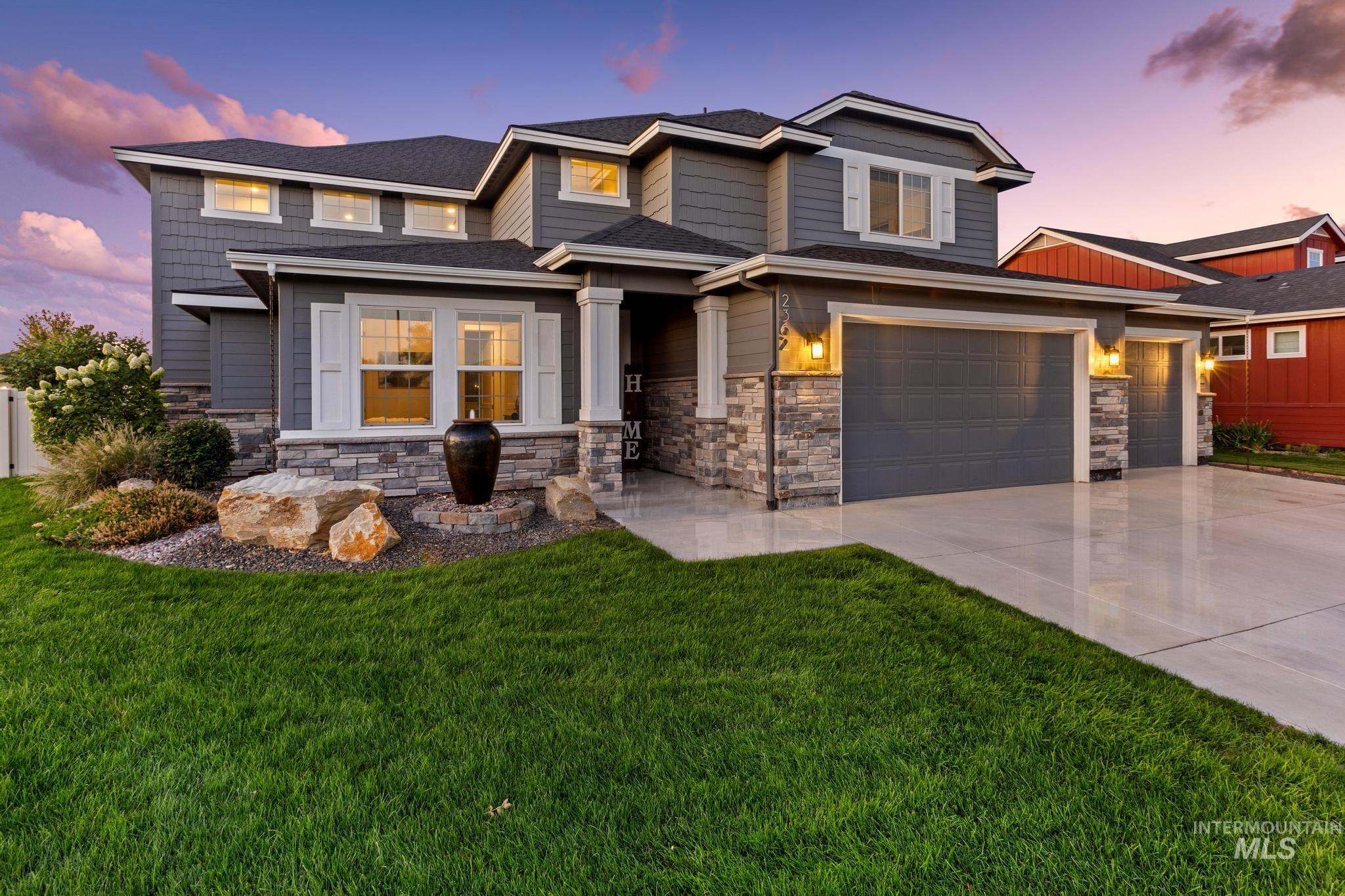 View of front of house with driveway, stone siding, and a yard