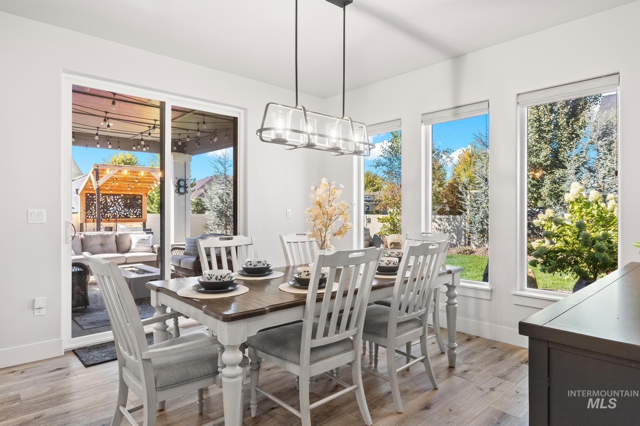 Dining area with light wood-style flooring, plenty of natural light, and a chandelier