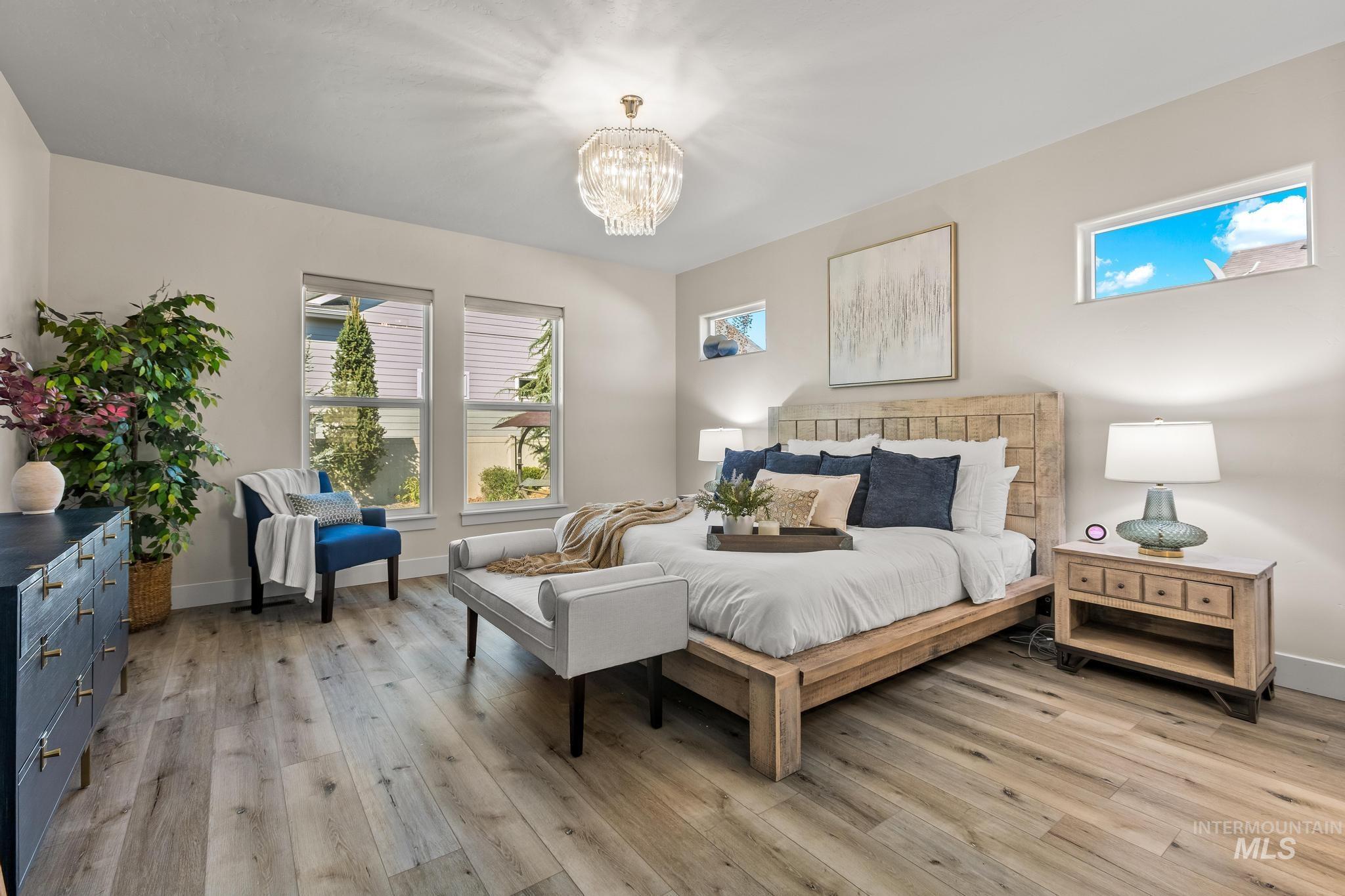 Bedroom with multiple windows, light wood-style floors, and a chandelier