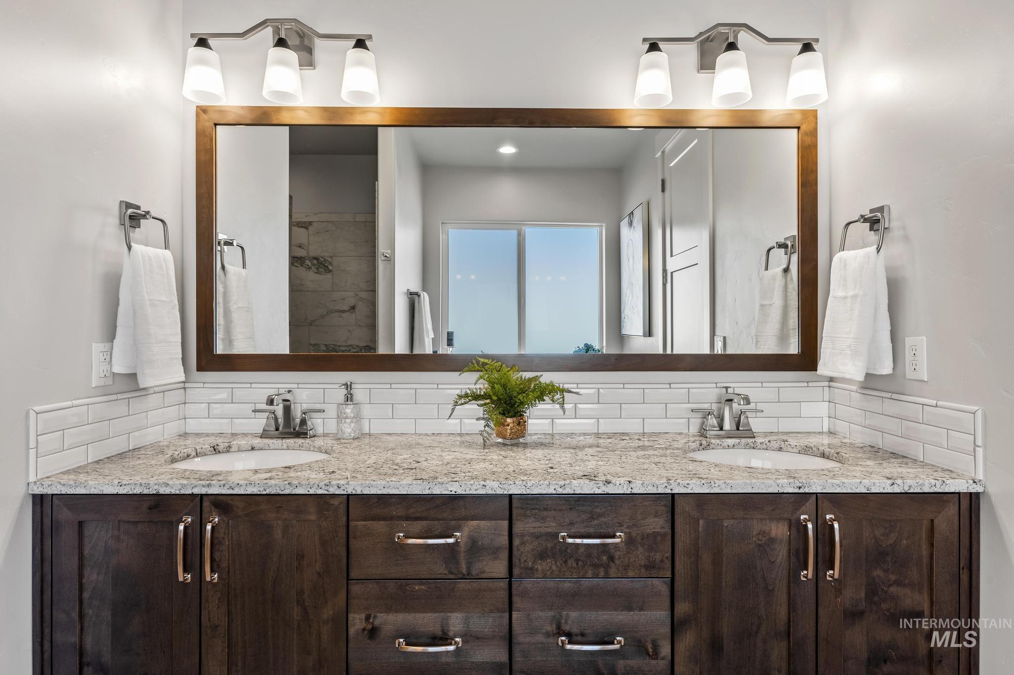 Bathroom with tasteful backsplash, double vanity, and a tile shower