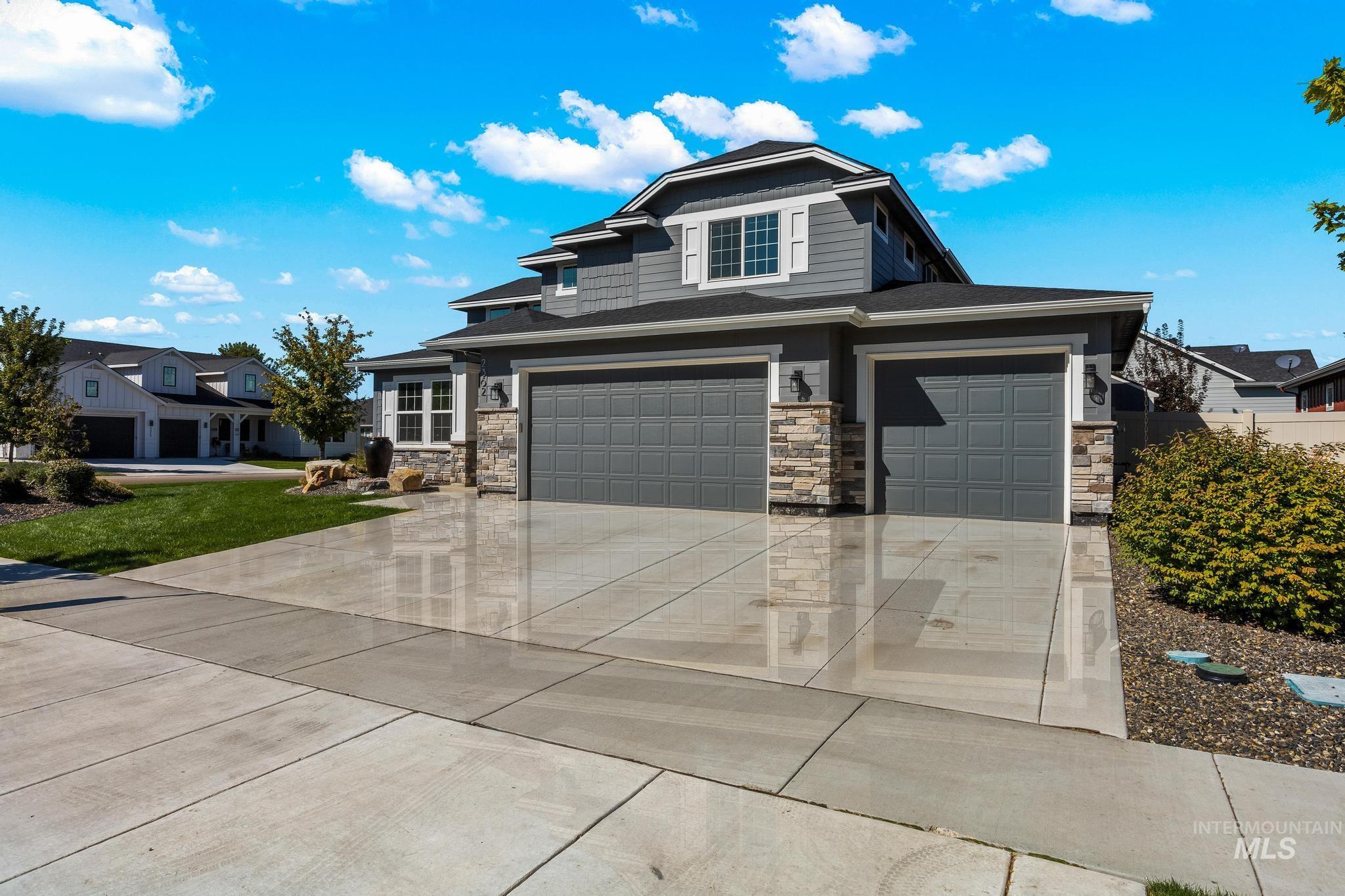 View of front of property featuring concrete driveway, stone siding, and an attached garage