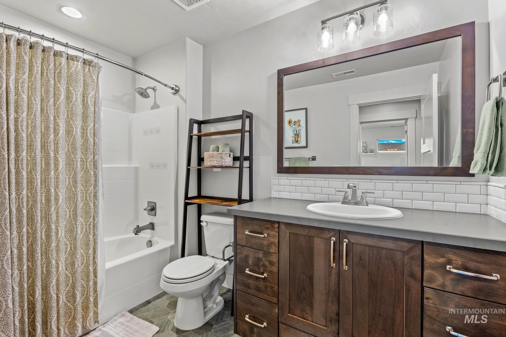 Full bathroom with shower / tub combo with curtain, vanity, and decorative backsplash