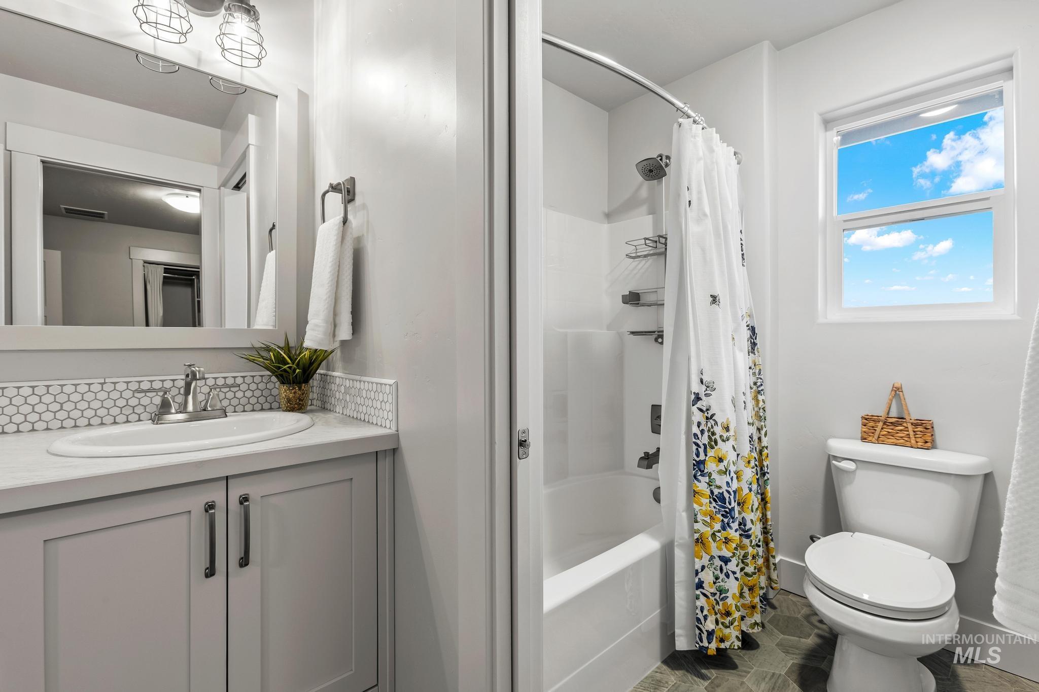 Bathroom featuring shower / tub combo, vanity, and decorative backsplash