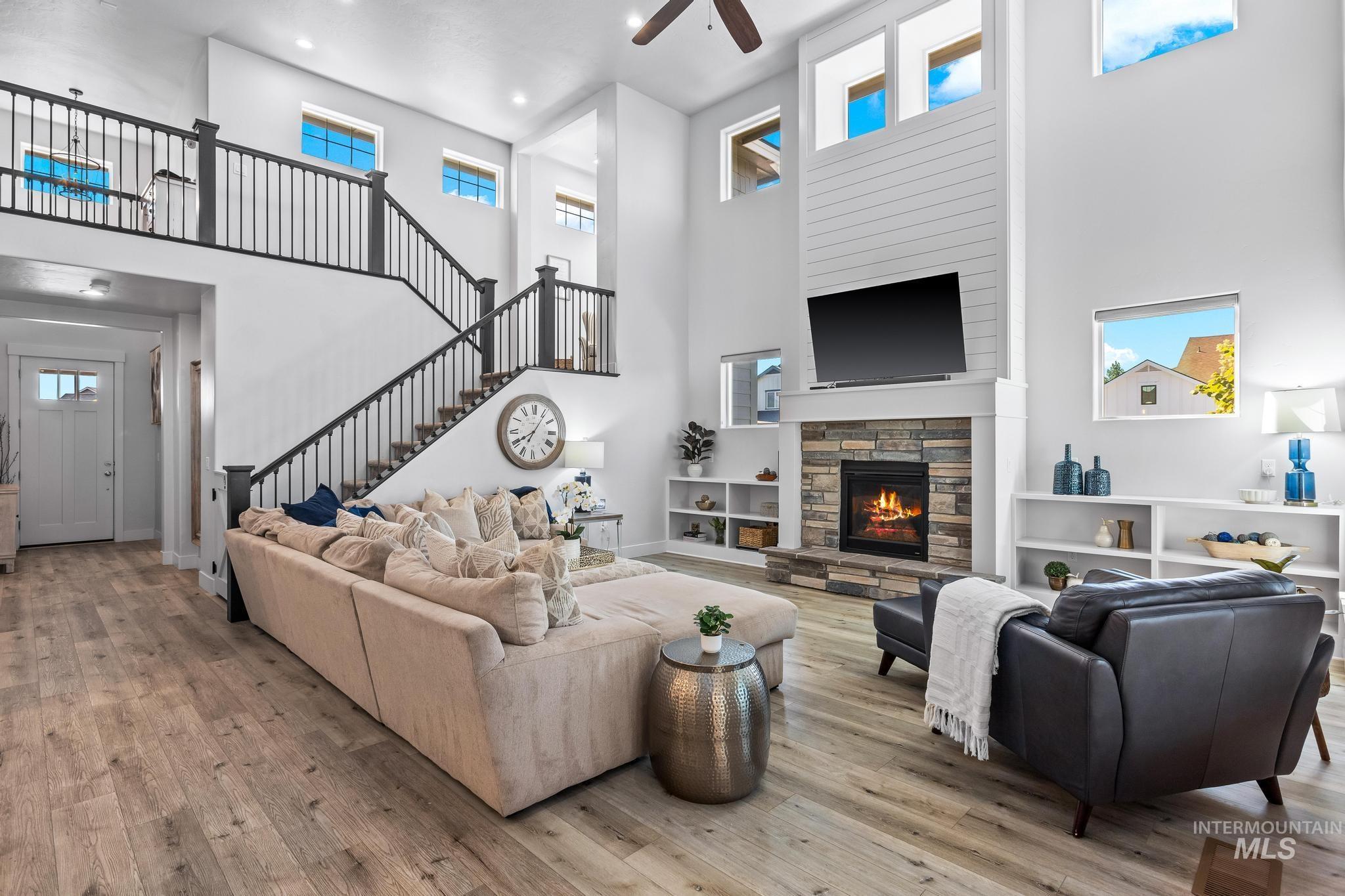 Living room with a towering ceiling, a fireplace, plenty of natural light, light wood-type flooring, and recessed lighting