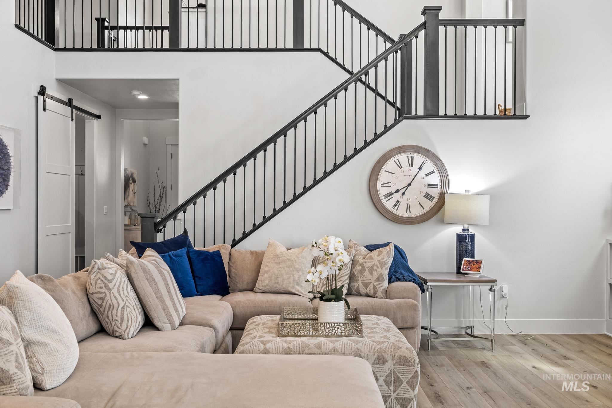 Living room with a barn door, a high ceiling, and wood finished floors