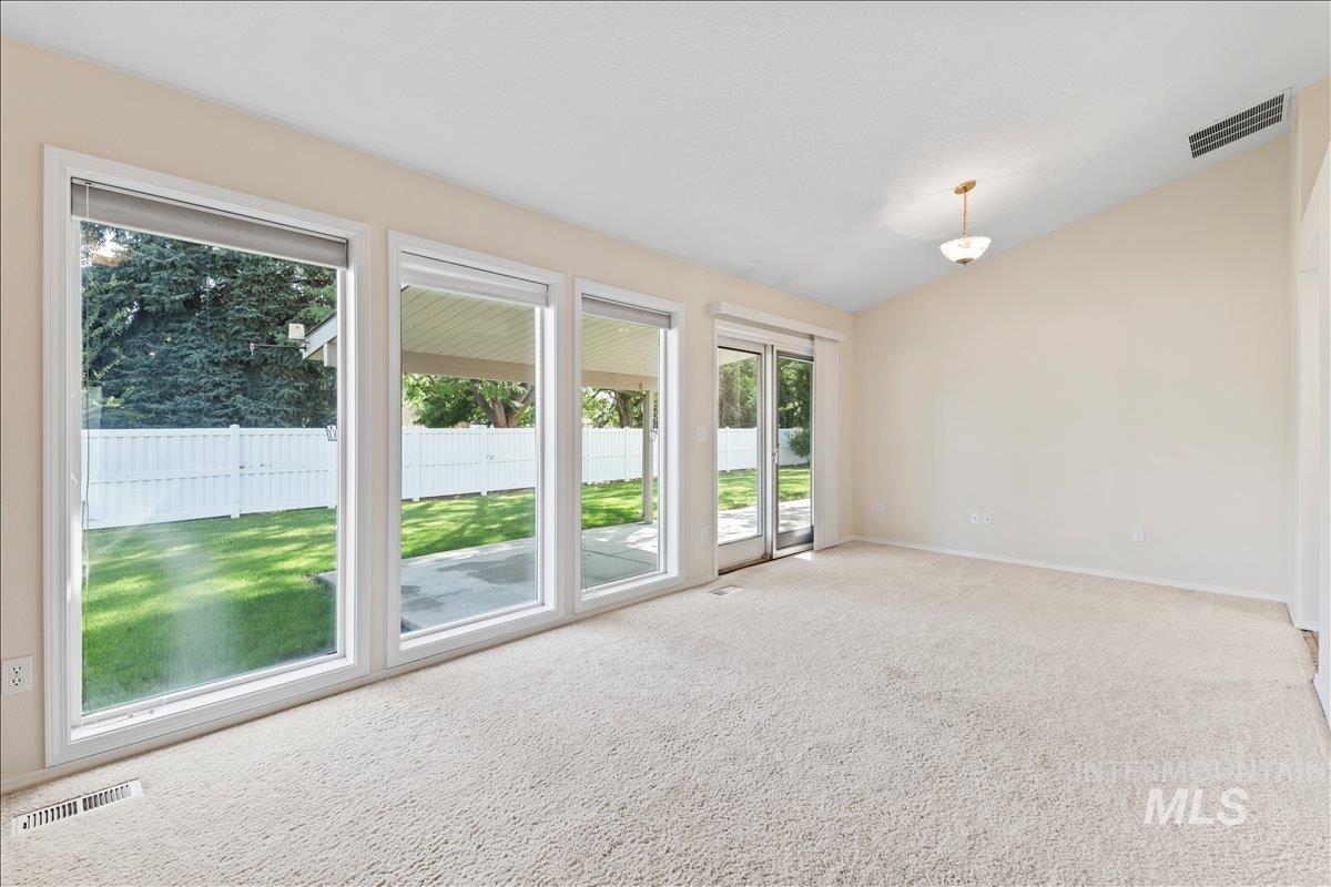 Carpeted spare room featuring lofted ceiling and baseboards