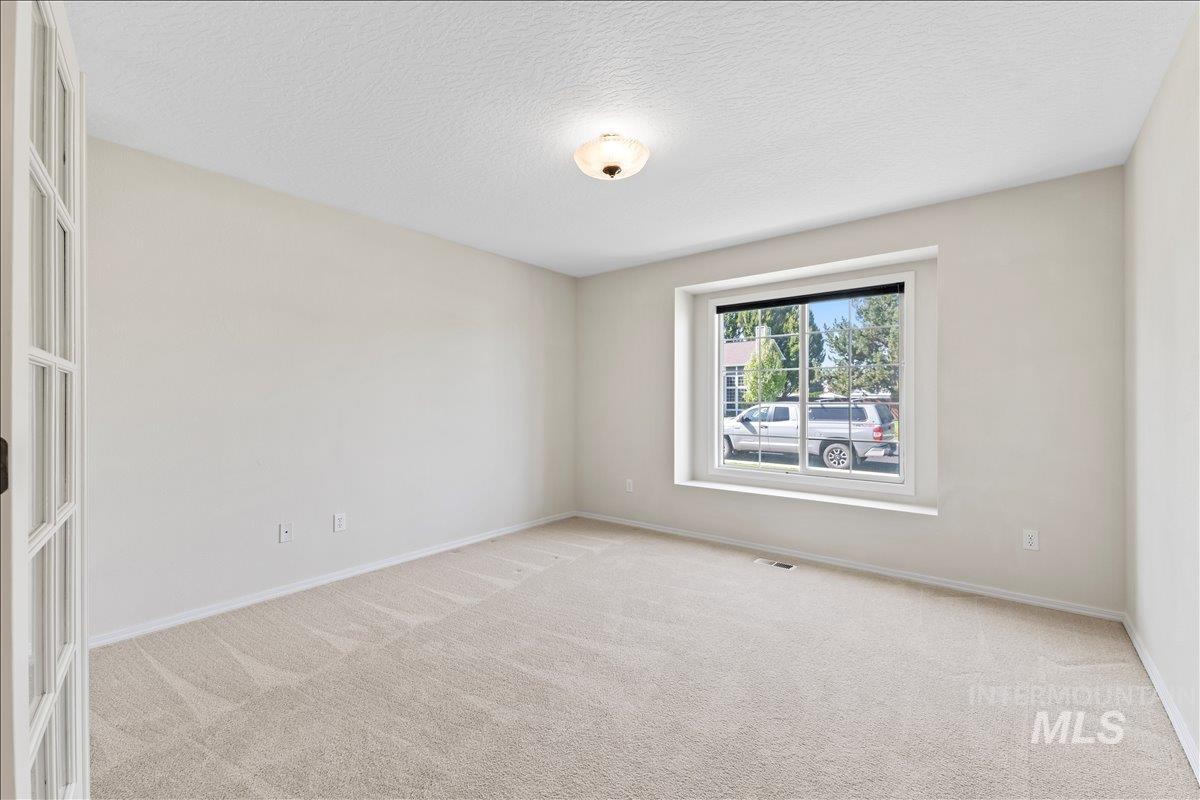Unfurnished room with light carpet and a textured ceiling