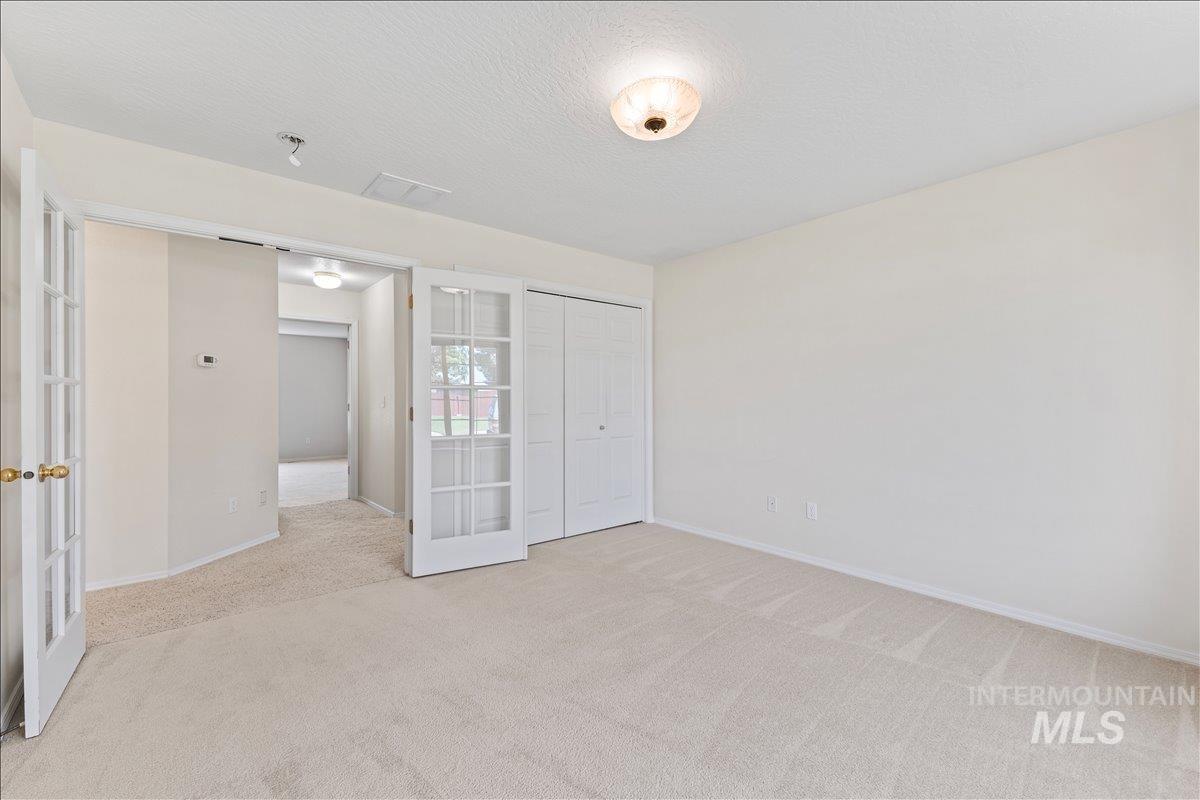 Unfurnished bedroom with french doors, a textured ceiling, carpet floors, and a closet