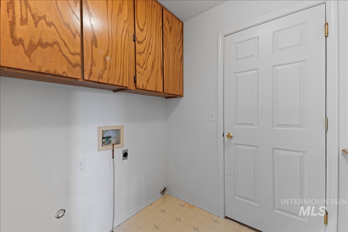 Washroom featuring cabinet space, washer hookup, light flooring, and electric dryer hookup