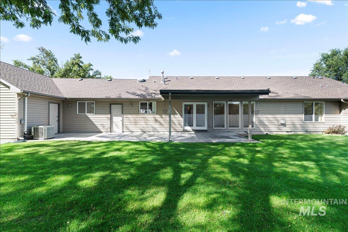 Rear view of house featuring a patio, a lawn, and roof with shingles