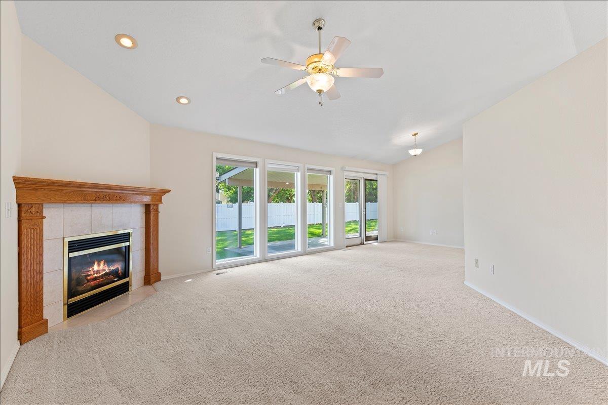 Unfurnished living room with recessed lighting, carpet flooring, a tile fireplace, lofted ceiling, and a ceiling fan