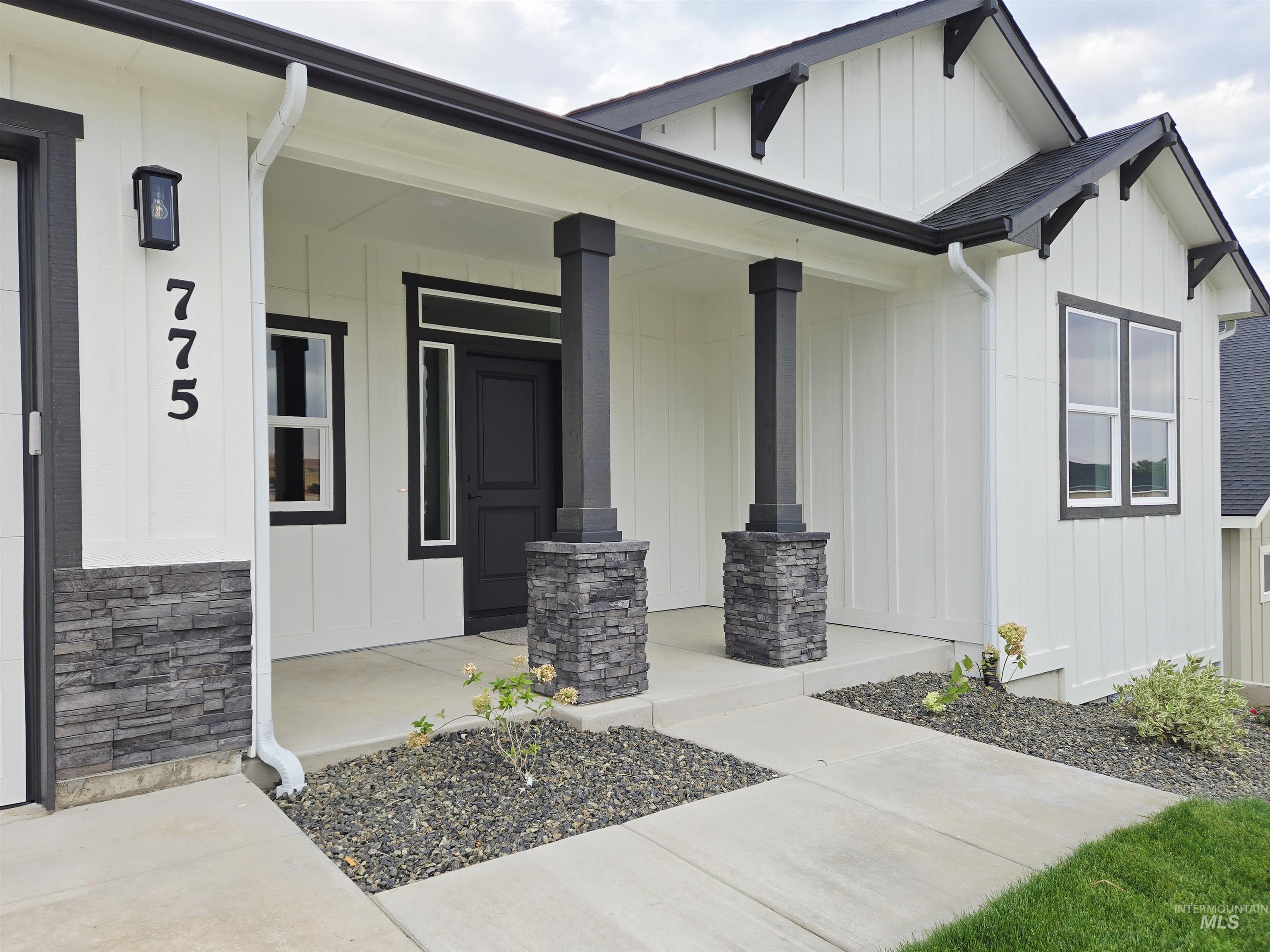 Entrance to property featuring a porch, board and batten siding, stone siding, and a shingled roof