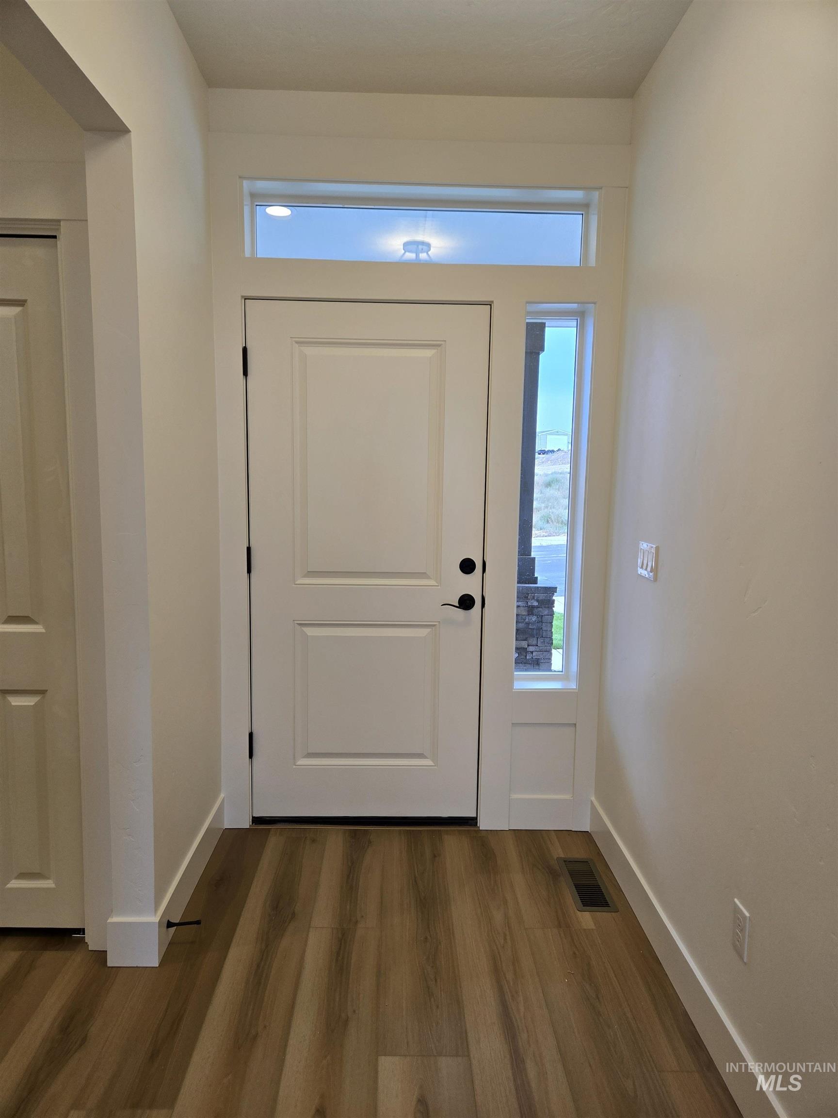 Entryway with dark wood-type flooring and baseboards