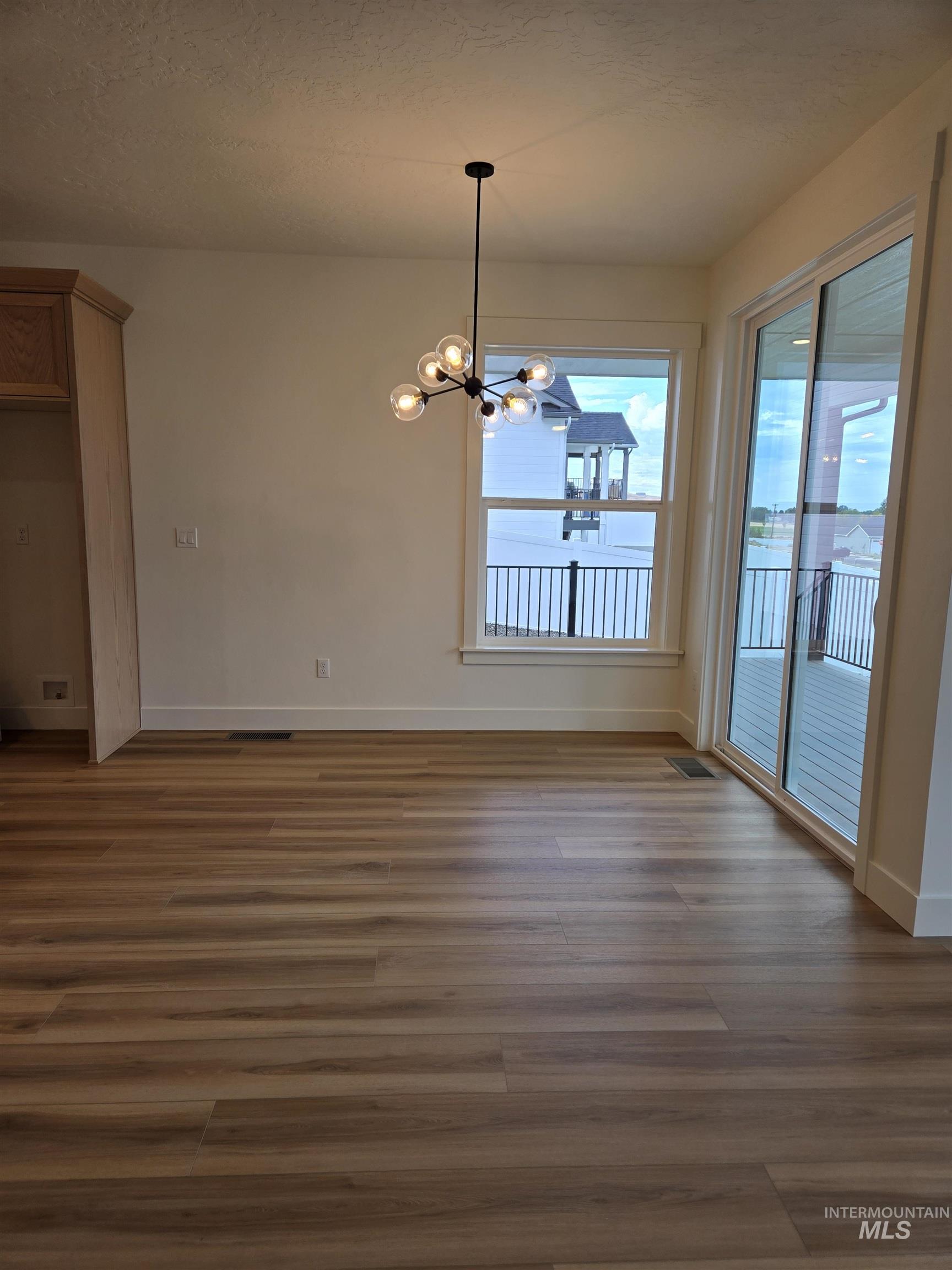 Unfurnished dining area with a chandelier, dark wood-style flooring, and a textured ceiling